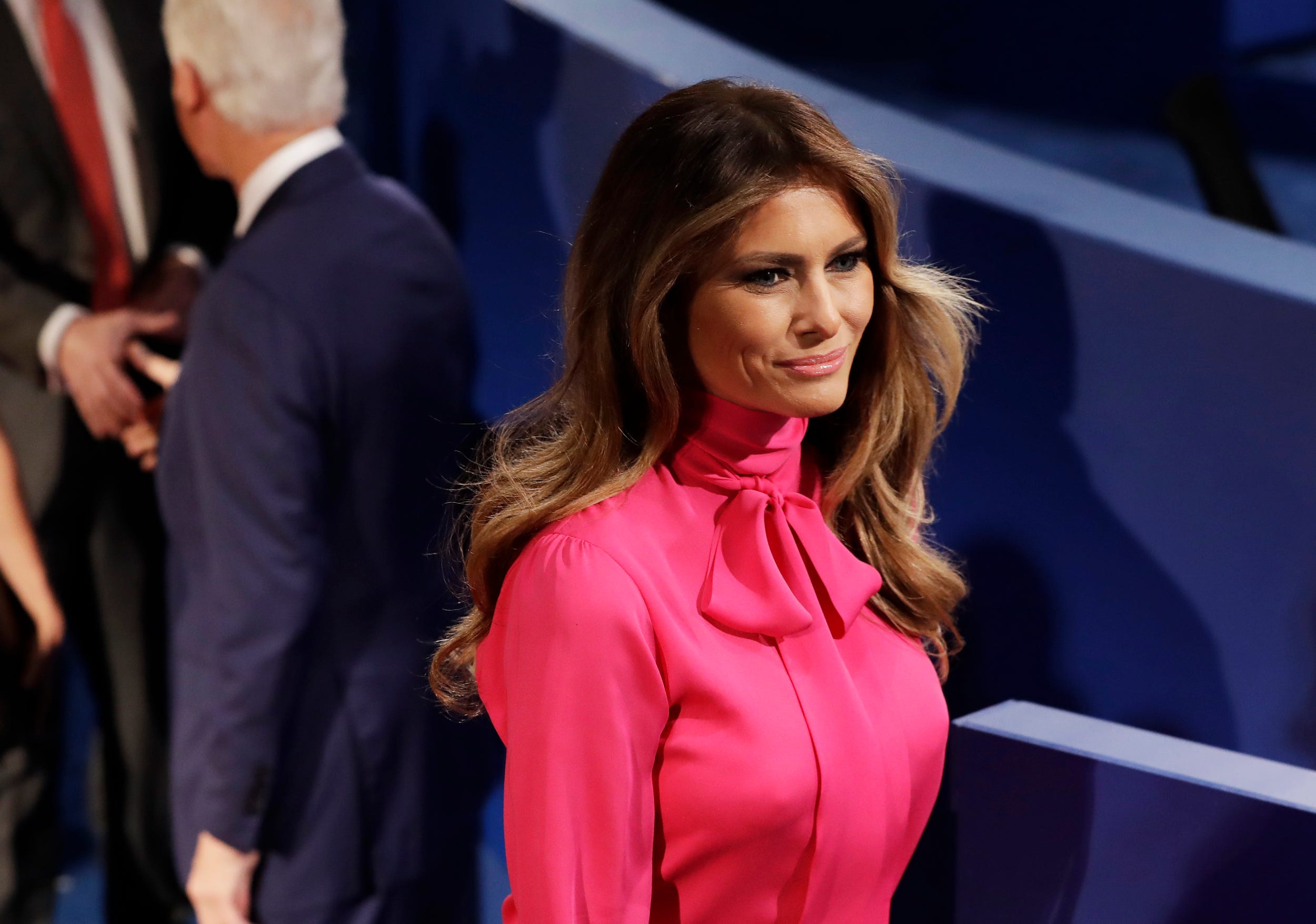 Melania Trump wears a pink blouse with a large bow at a presidential debate.