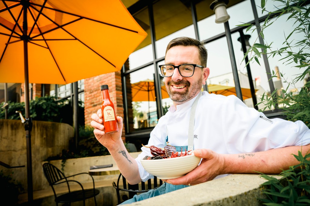 Chef Michael King shows off some hot sauce and a bowl of dried and smoked chilies used in a recipe.