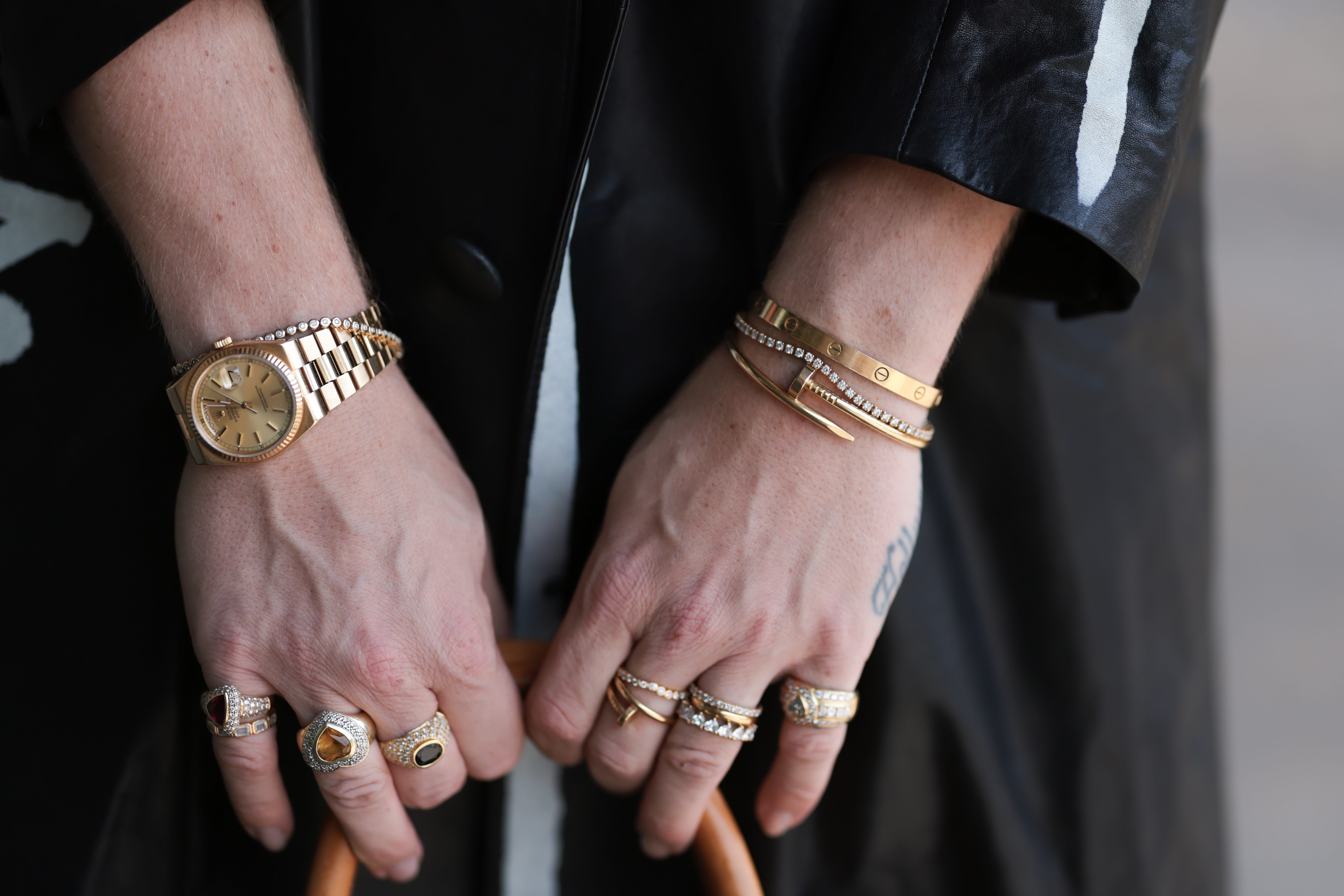 Close up of hands holding a bag - person is wearing a watch, bracelets, and many stacked rings