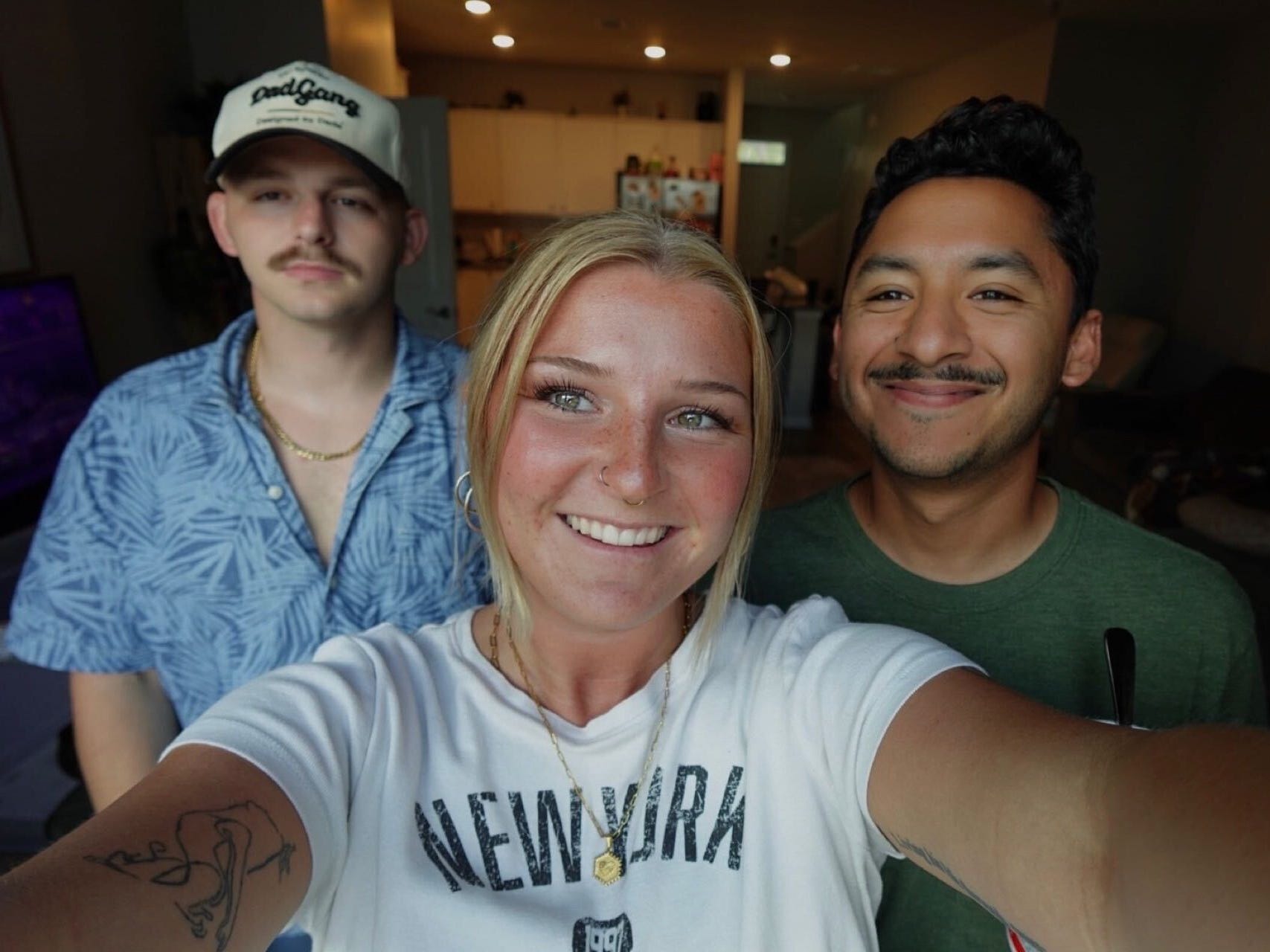 A selfie of a woman with two men standing behind her.