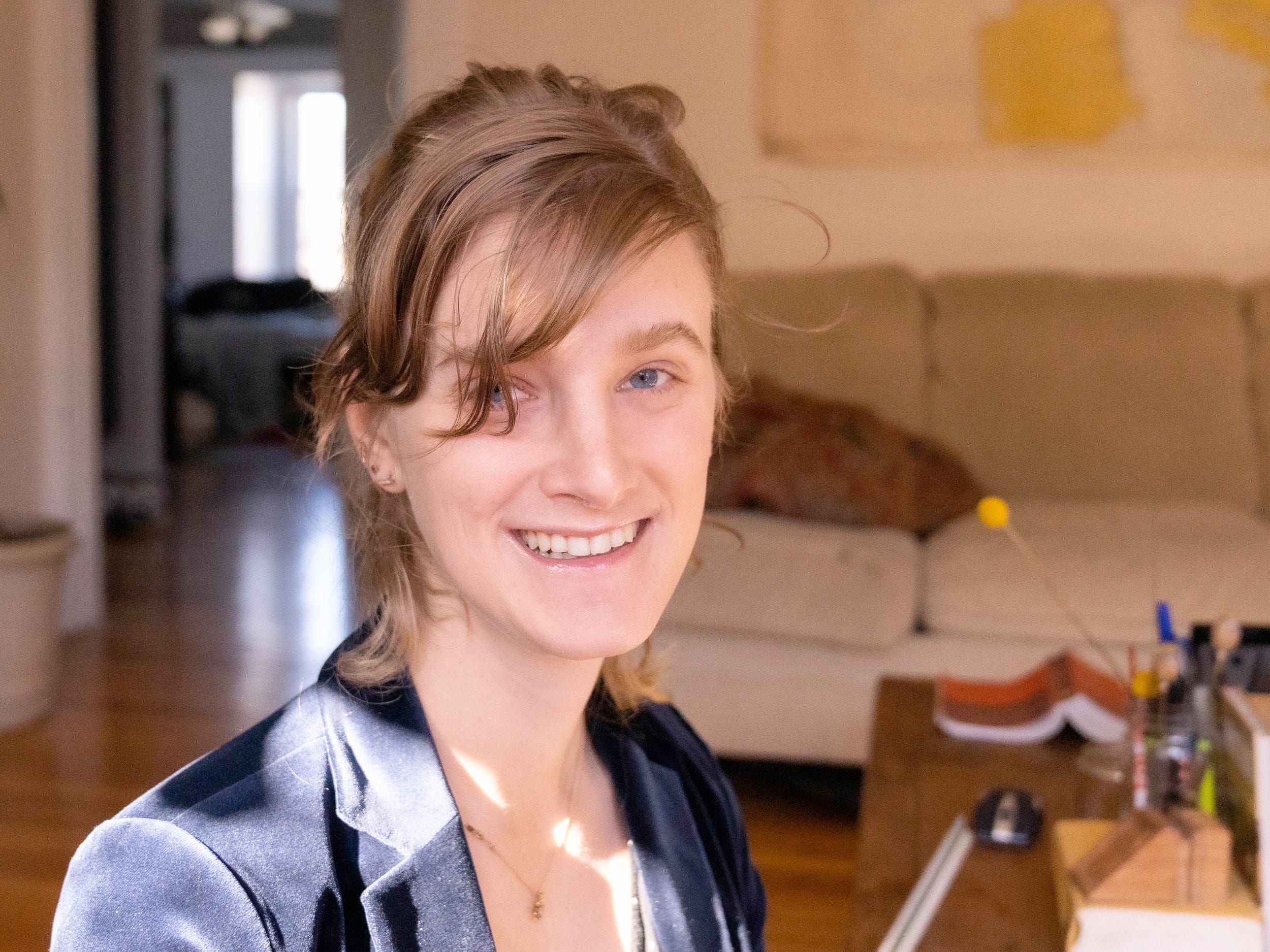 Lily Clifford wears a navy blazer while posing in a living room