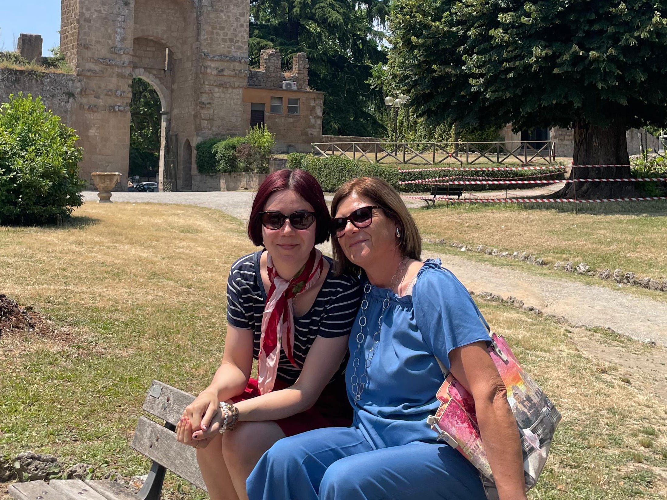The author and her mother sitting on a bench in Italy outside.