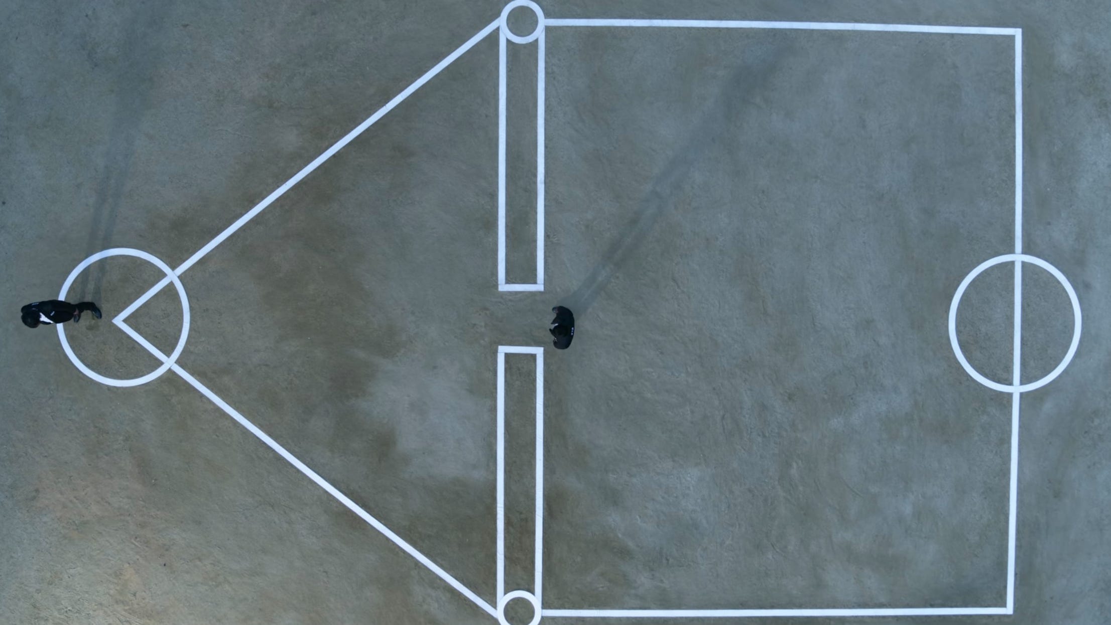 A still of "Squid Game" season one episode nine showing an overview of a grid with two men in it.