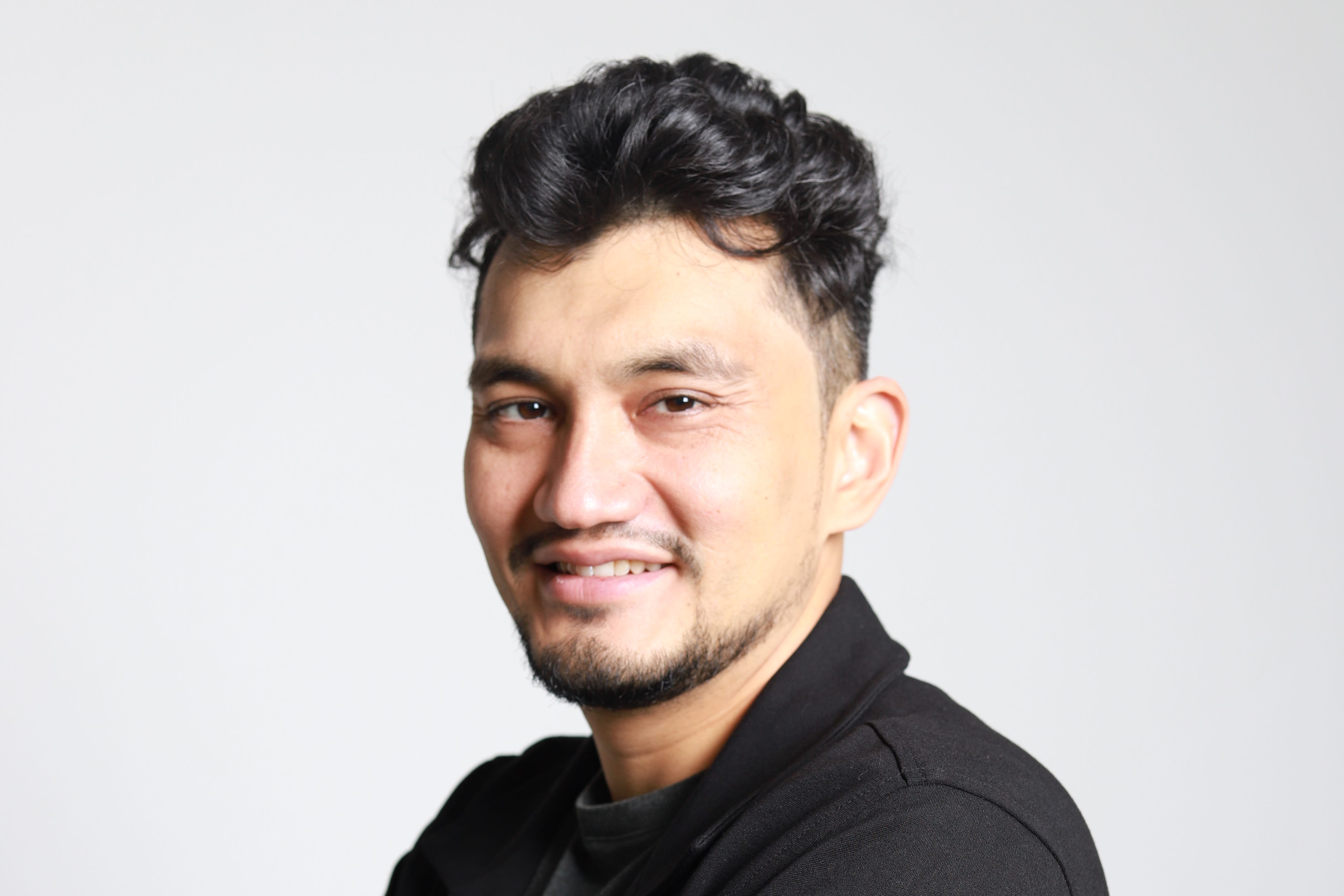 headshot of a man in a black outfit with a white background