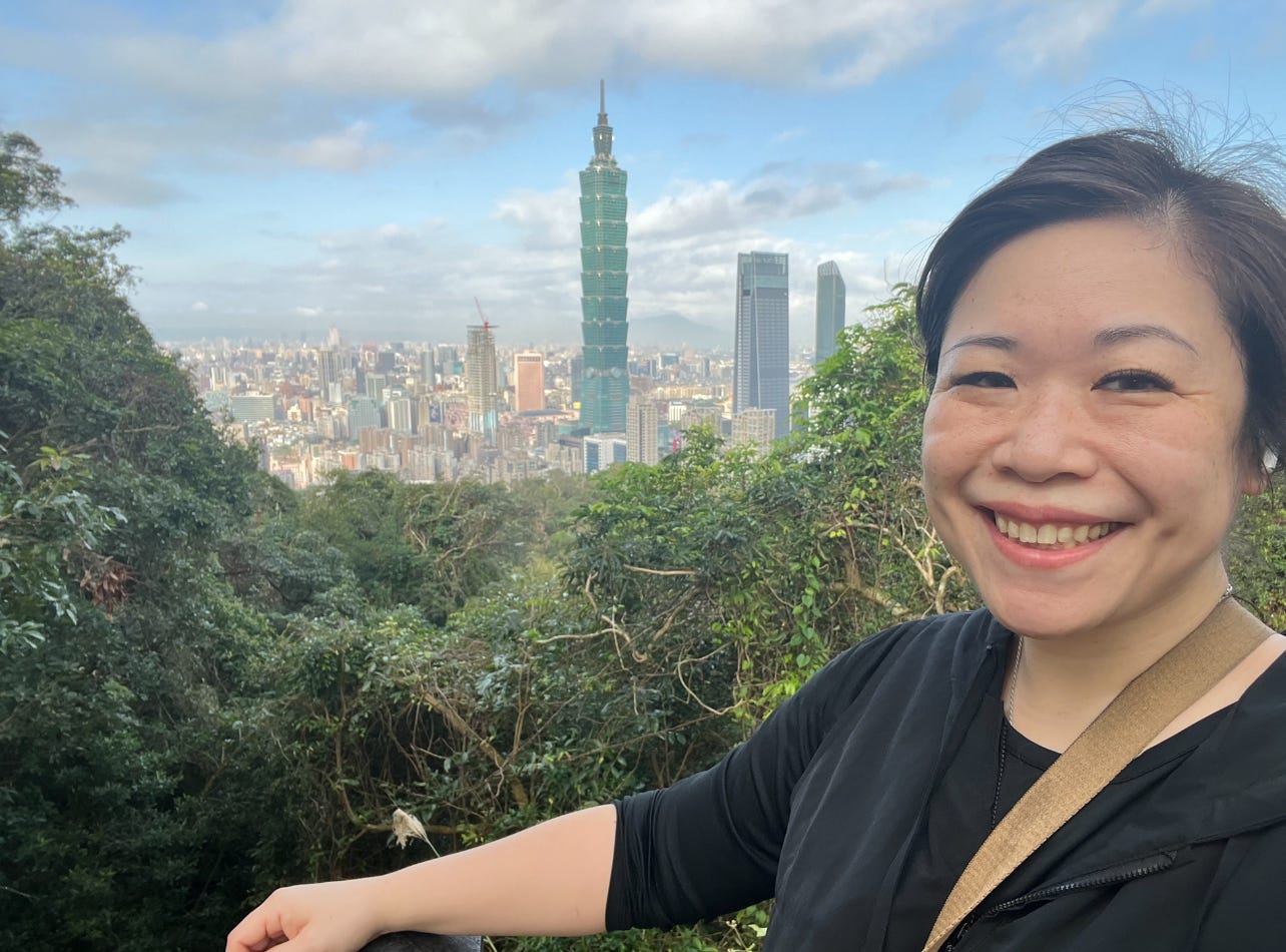 A woman posing with Taipei 101 and Taipei in the background.
