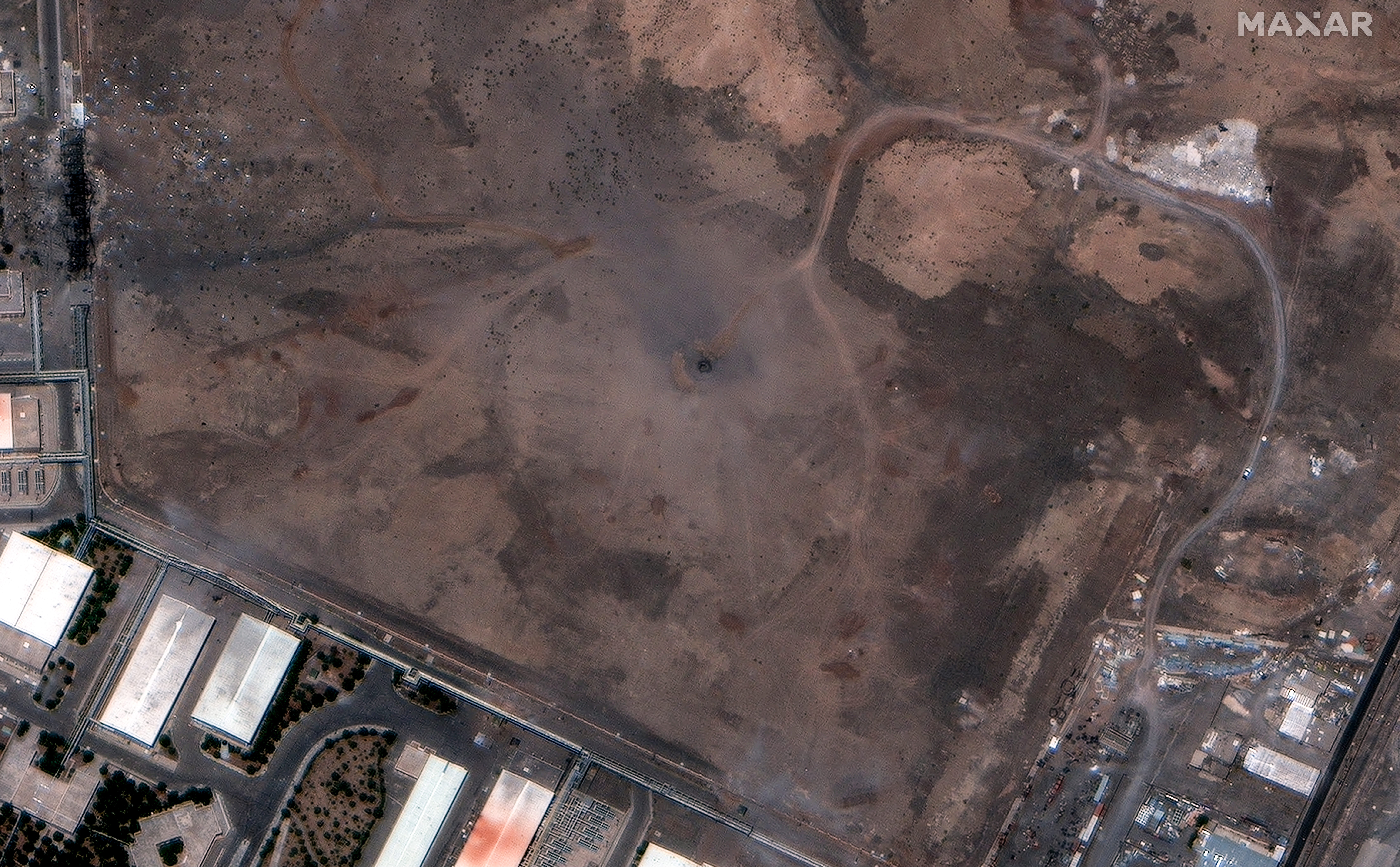 A satellite image of a crater with buildings around it.