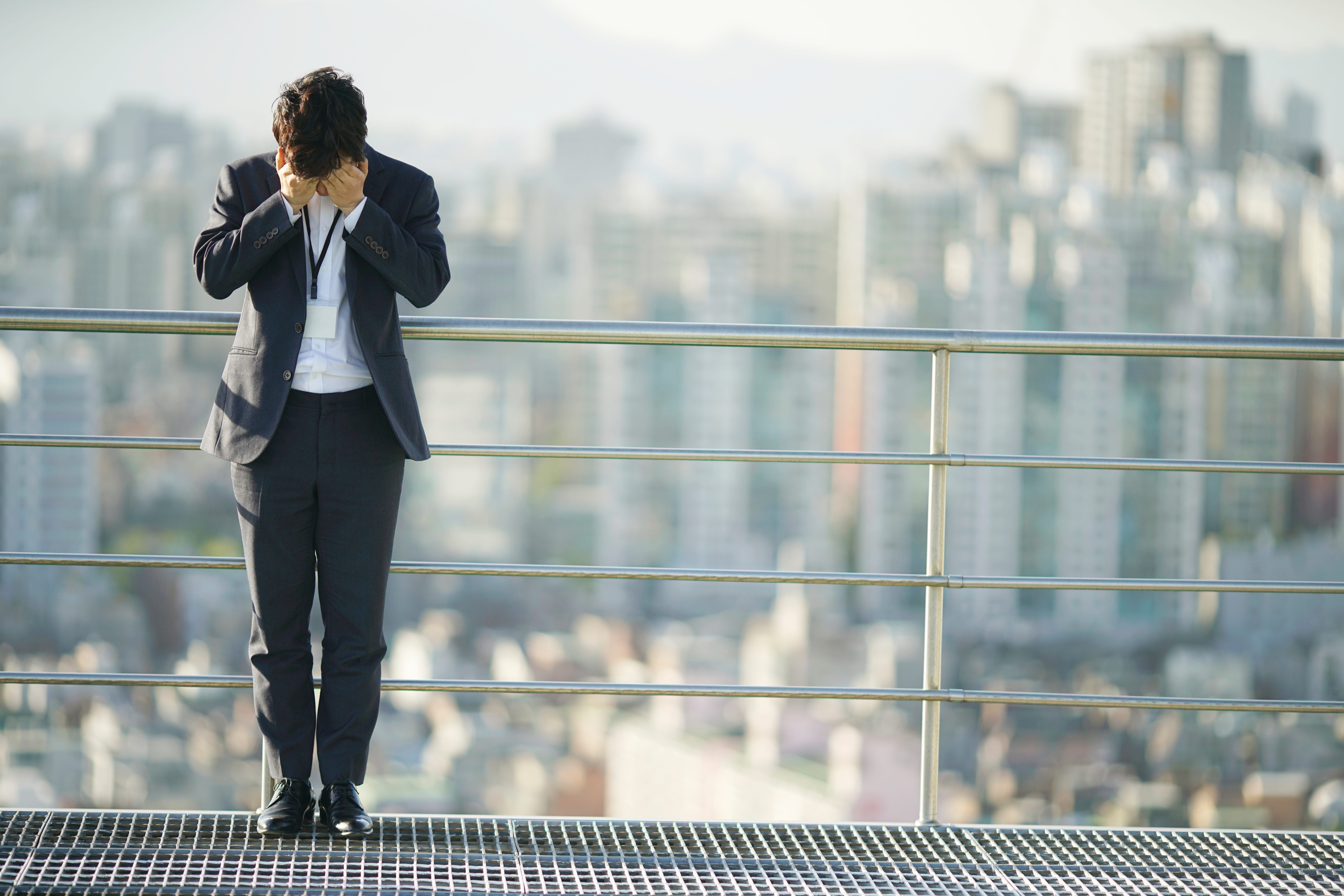 Businessman covers face while on rooftop