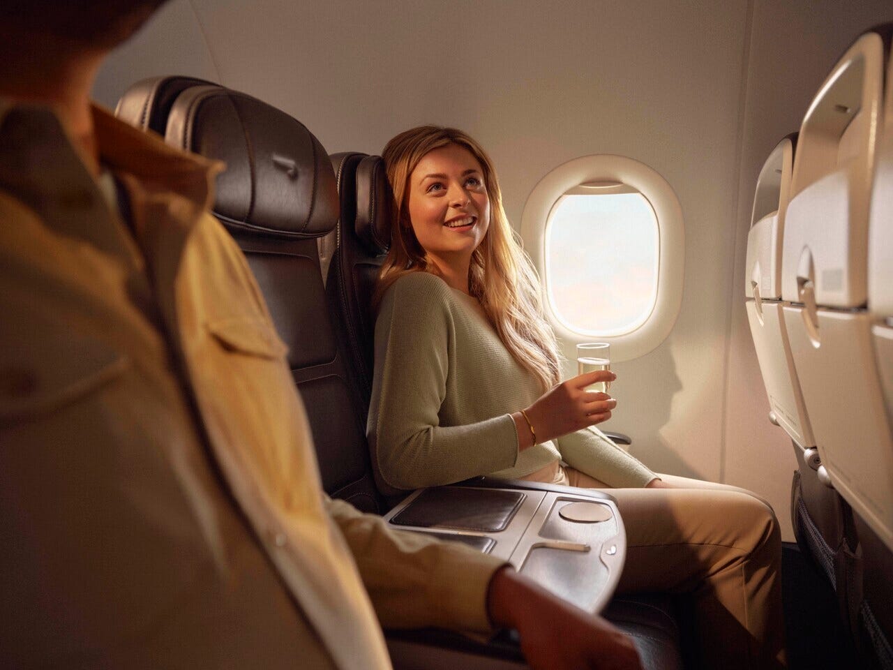 A female British Airways passenger sits in the window seat of a Club Europe cabin, with a divider placed on the middle seat.