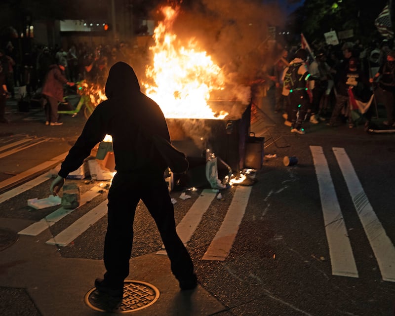 Protesters set fire to a dumpster in Seattle—unrest in response to ICE raids have spread to cities across the nation after beginning in Los Angeles.