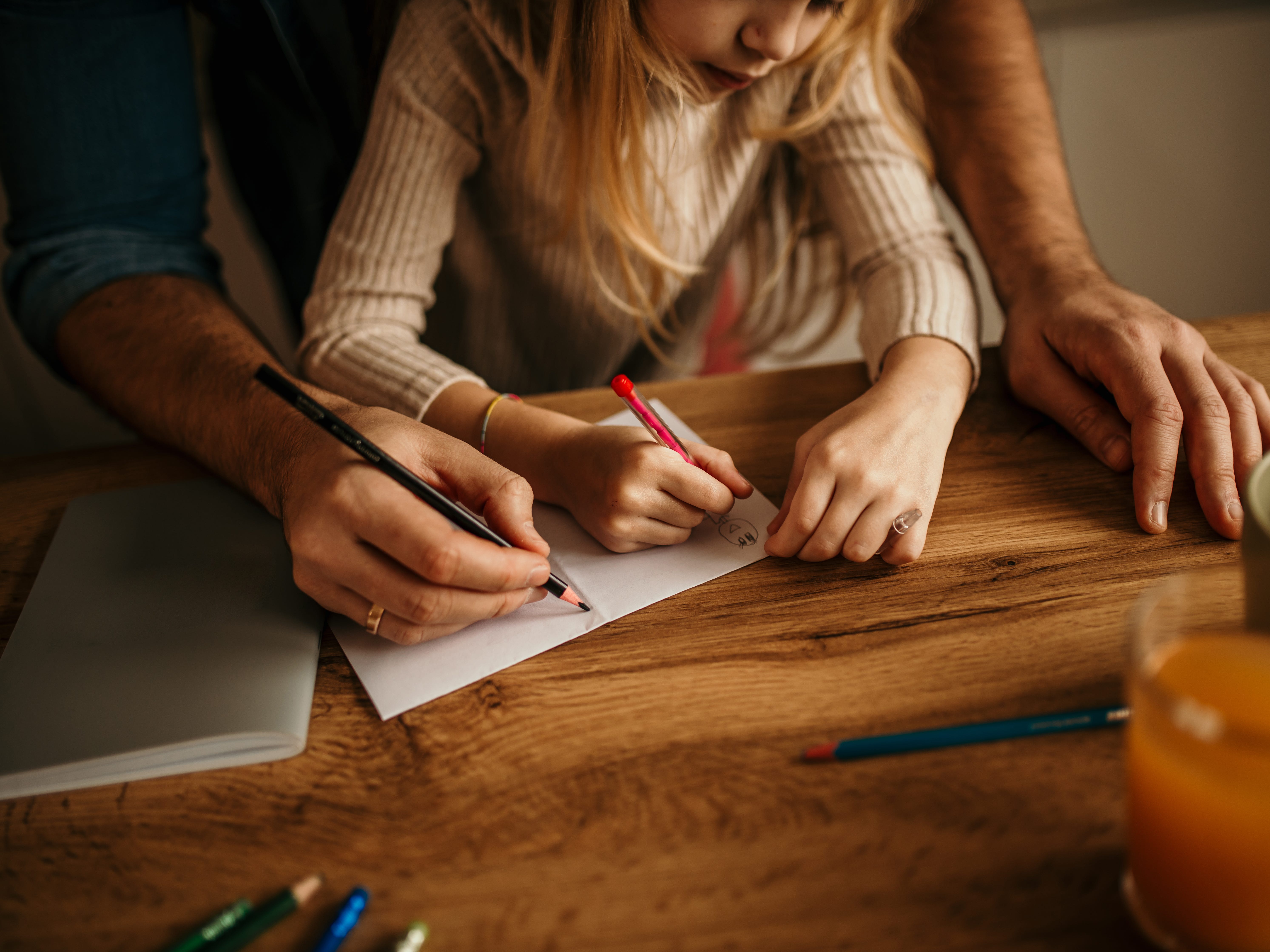A parent and child sitting at a table writing a thank-you note.