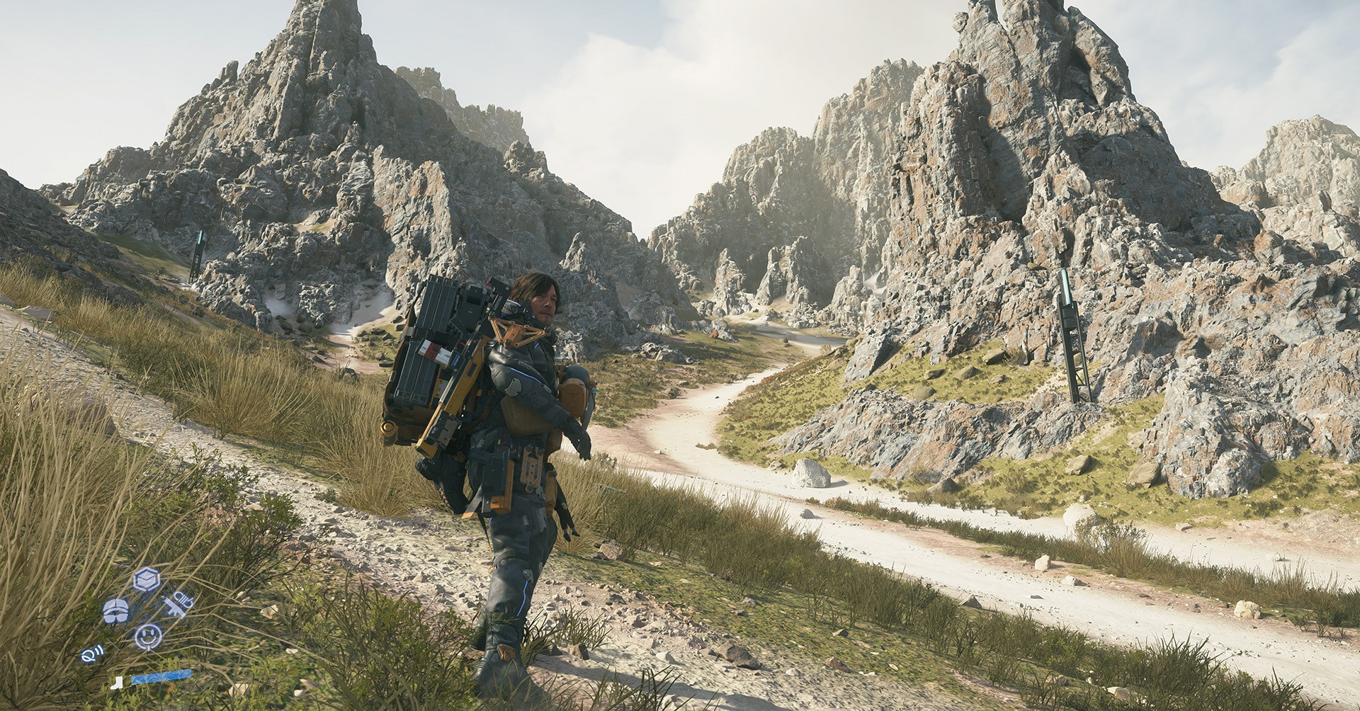 Sam Bridges stands before a rugged mountain landscape in Death Stranding 2