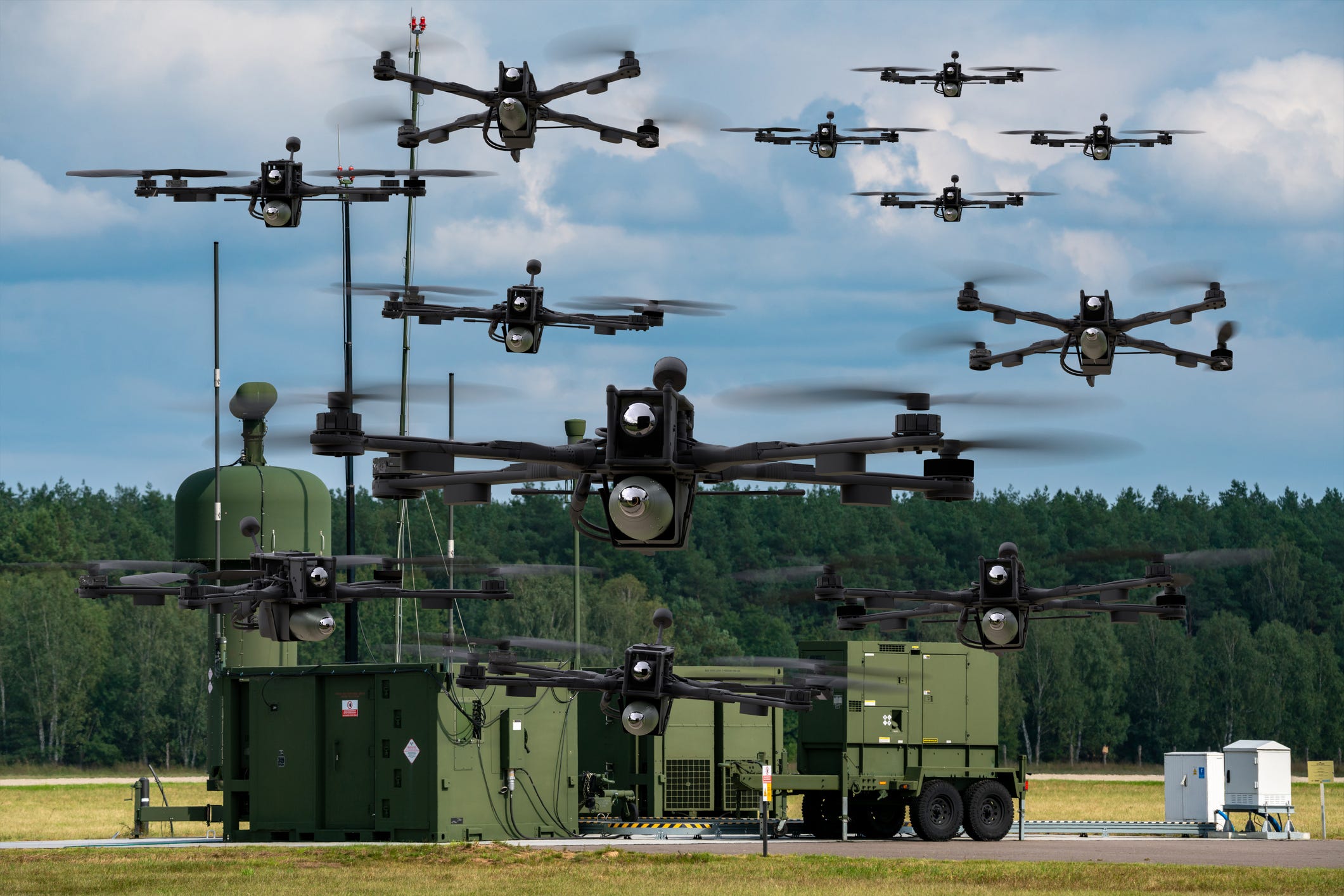 US Army drones at a military base in a clearing with trees in the background.