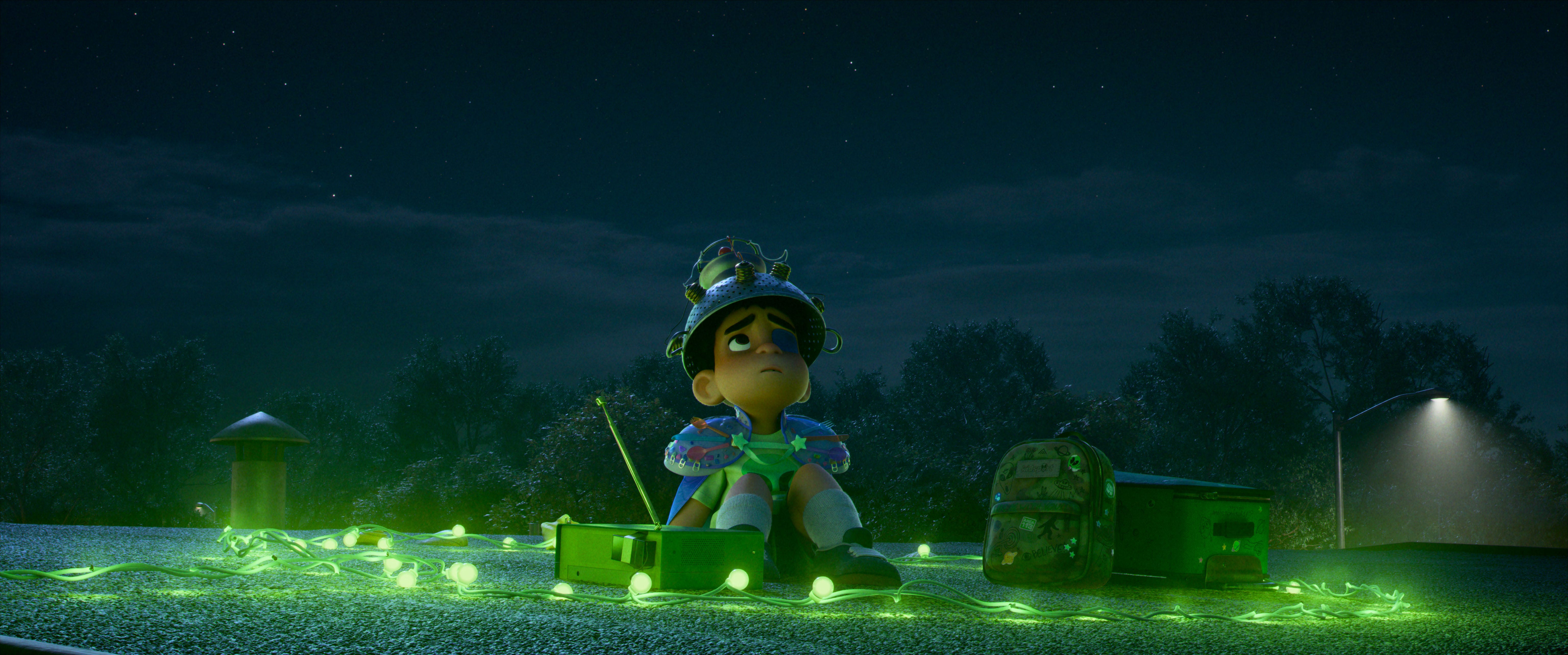 A still from "Elio" showing a boy with a black eye sitting in a field.