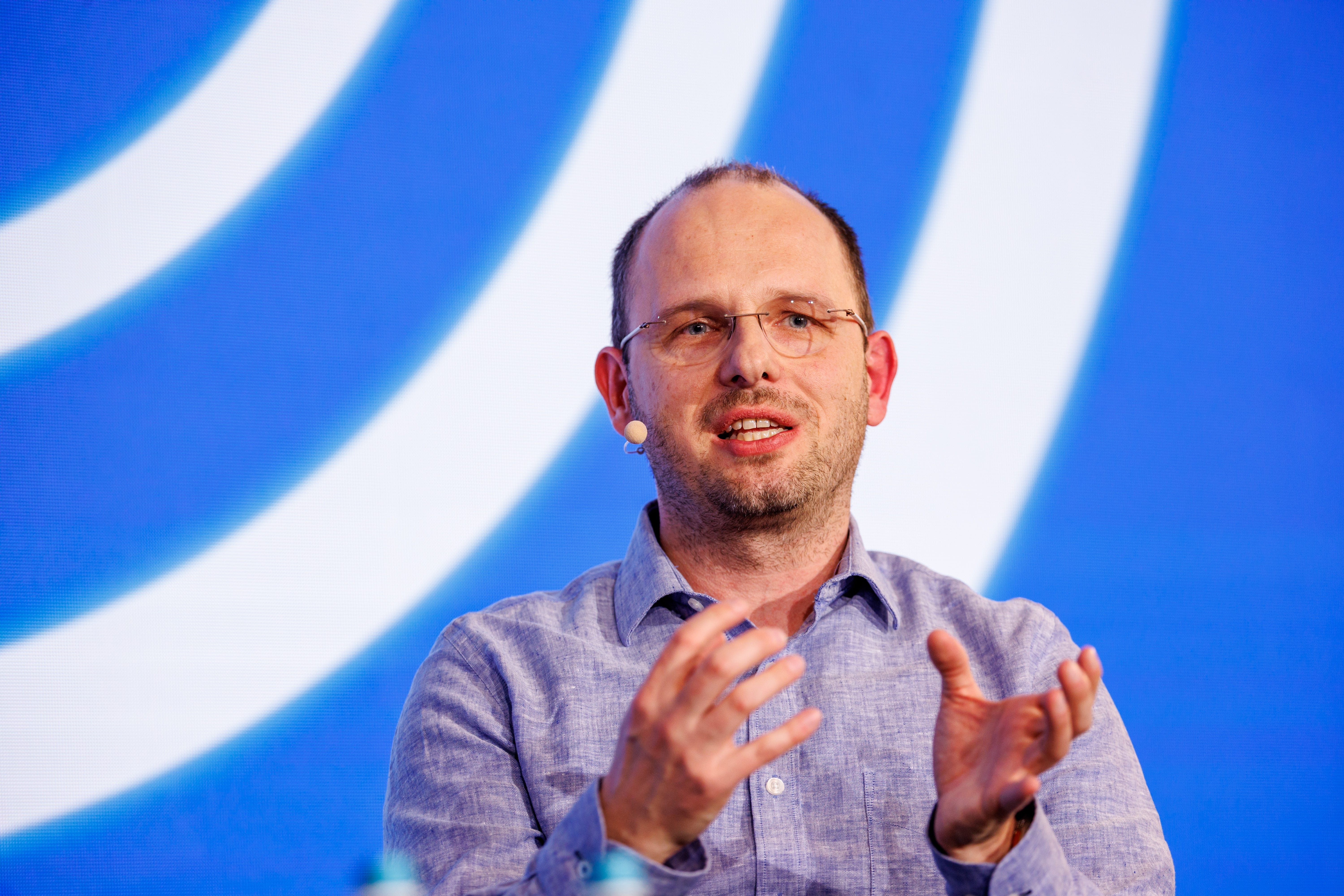 Thomas Dohmke, CEO of Github, speaks at the Digital Life Design (DLD) innovation conference. His hands are elevated in front of his chest, and he is mid-speech.