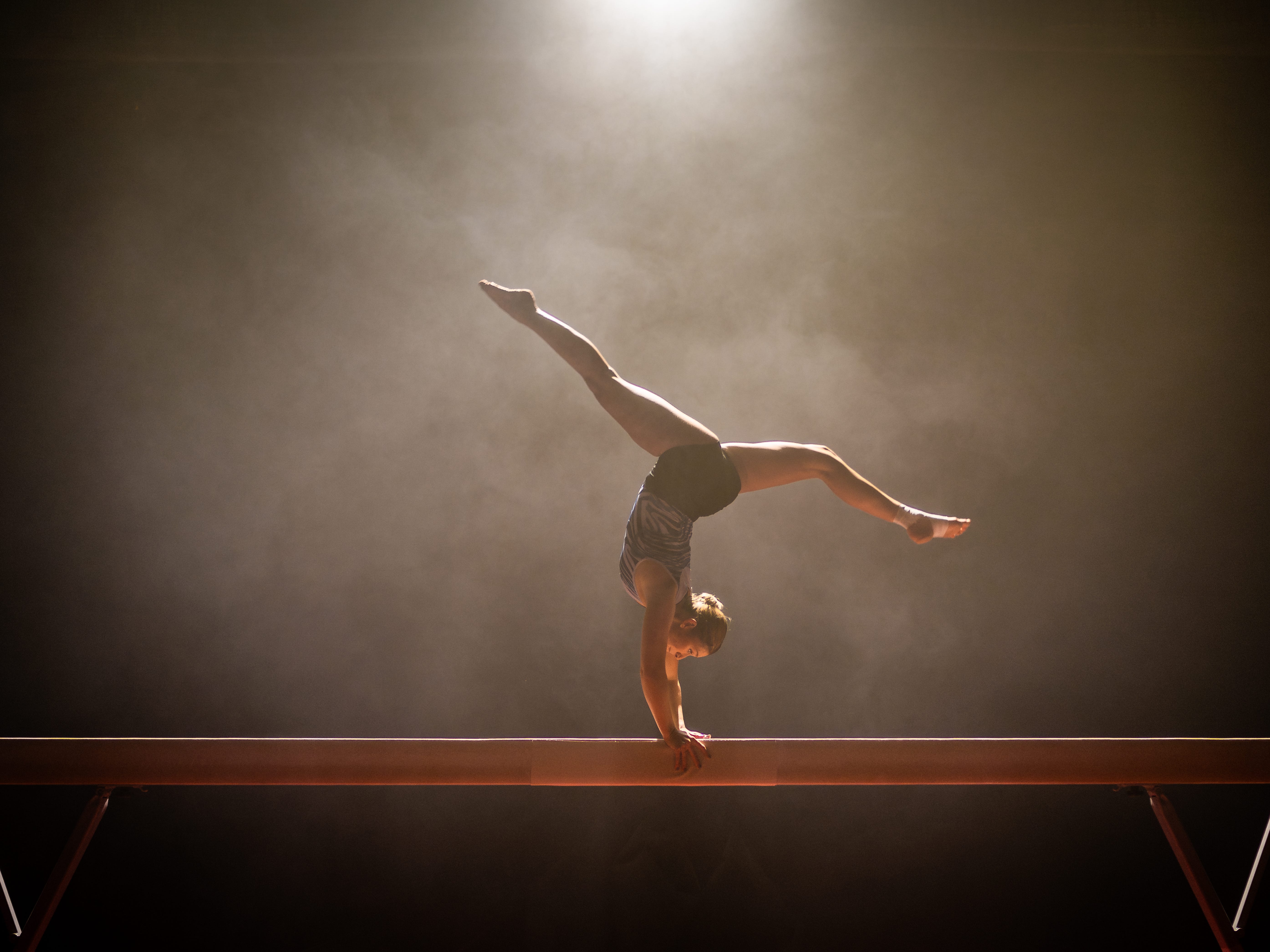 a gymnast upside down on the balance beam