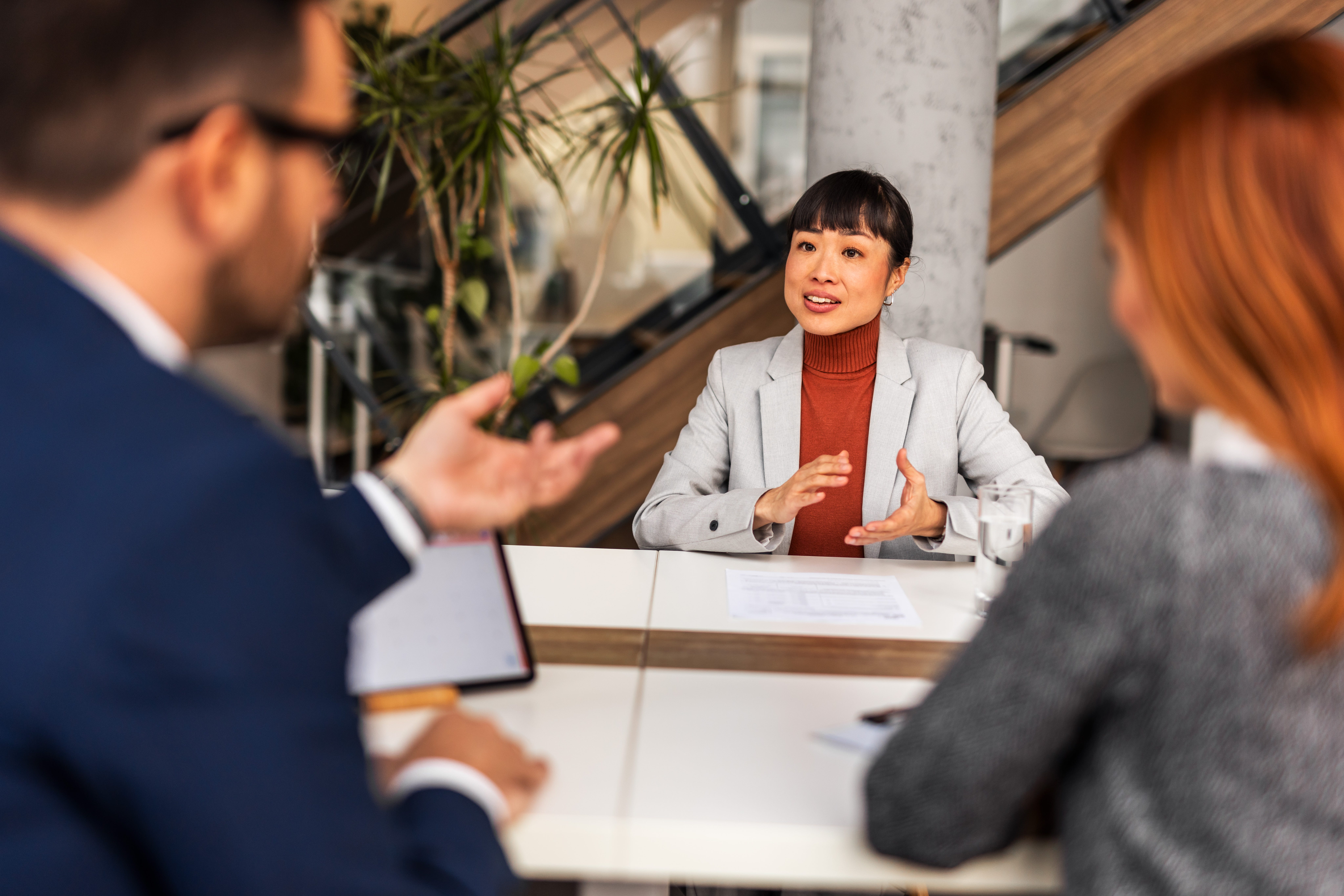 A woman sitting at a table facing a man and a woman during an interview
