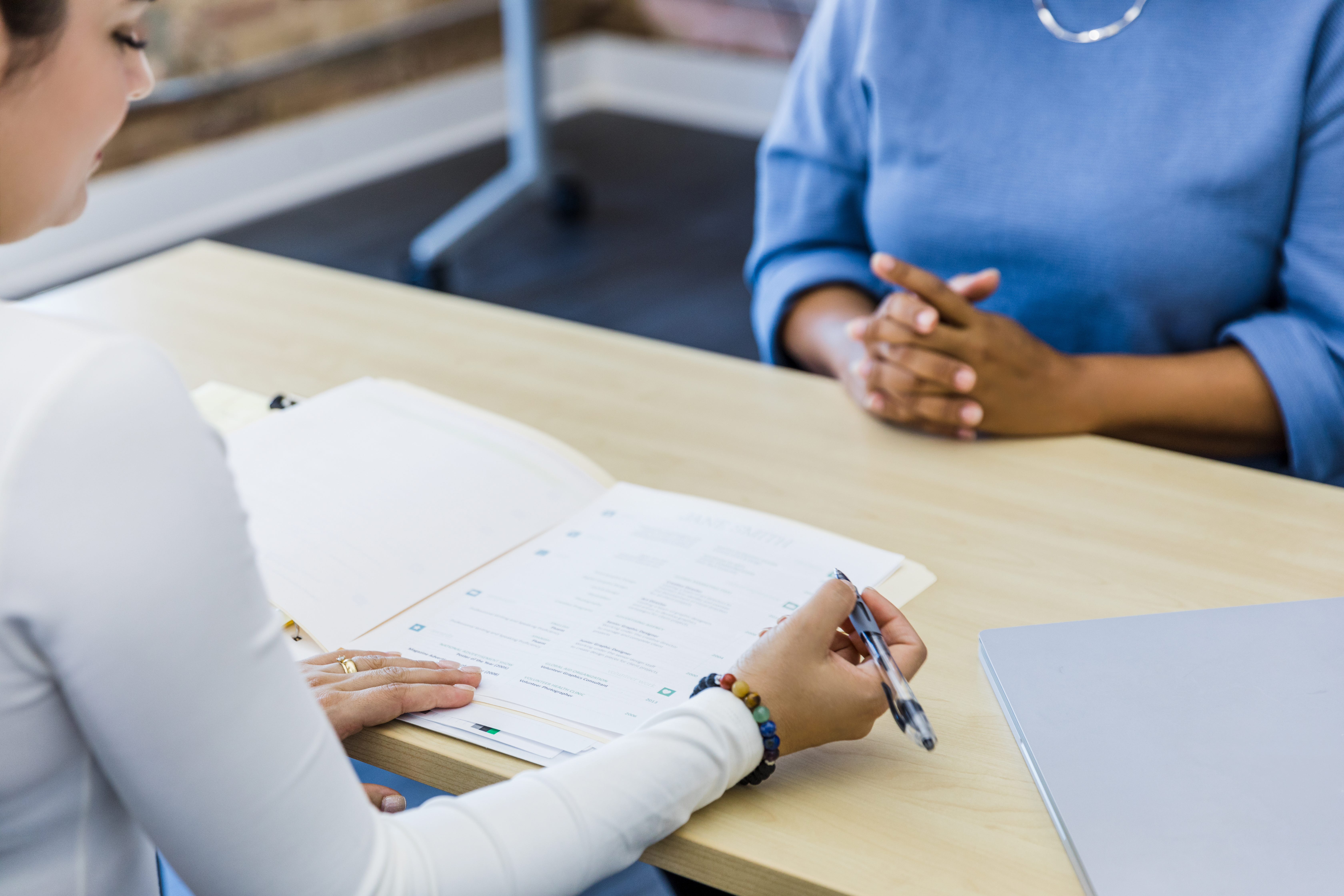 Person writing on paper on the table interviewing someone