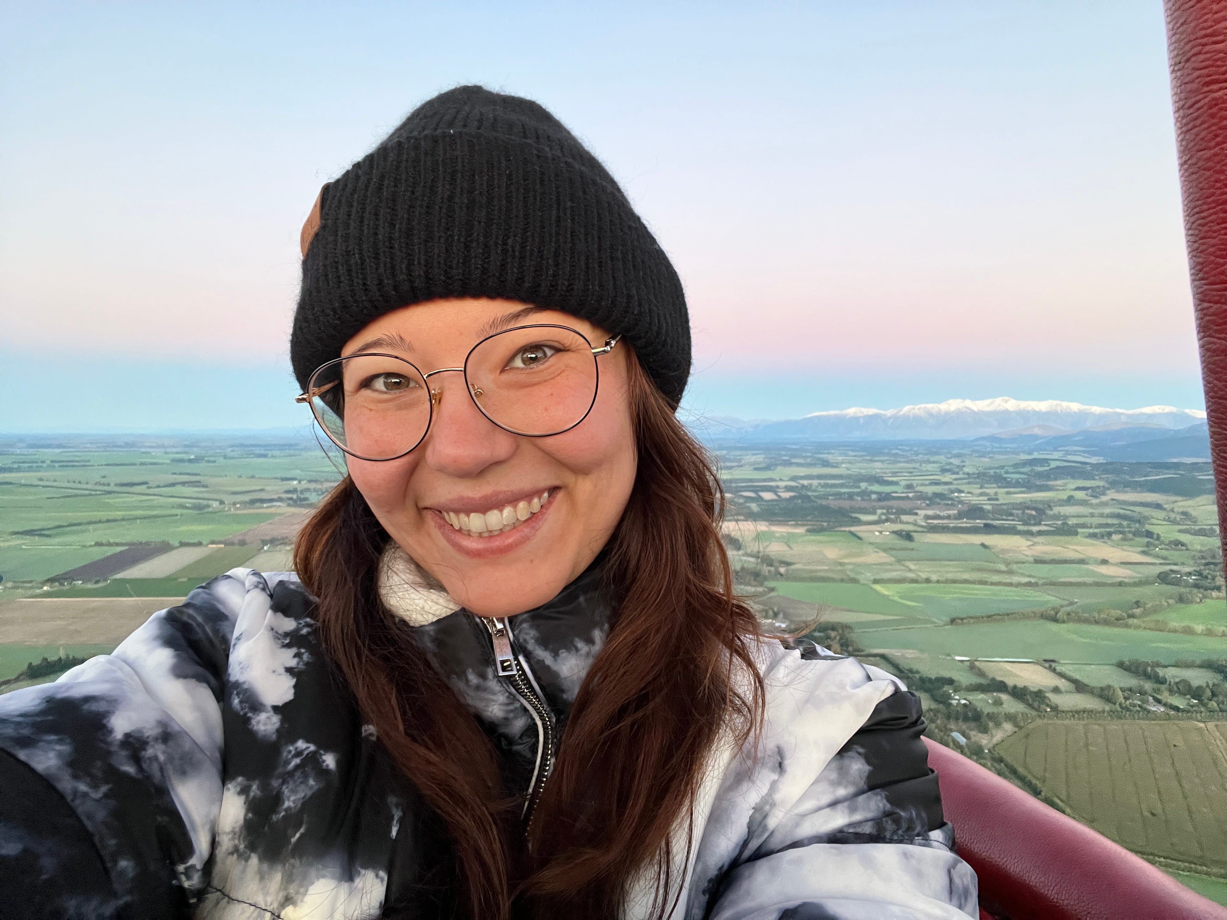 Author Ashley Probst smiling on a hot air balloon with colorful sky behind her