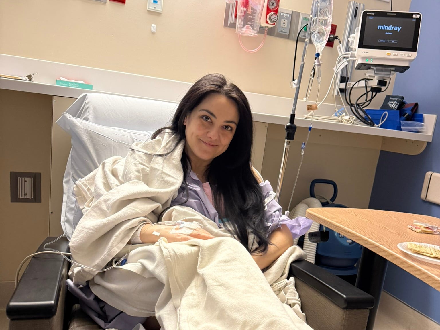 The author sitting in a chair in a hospital during treatment.