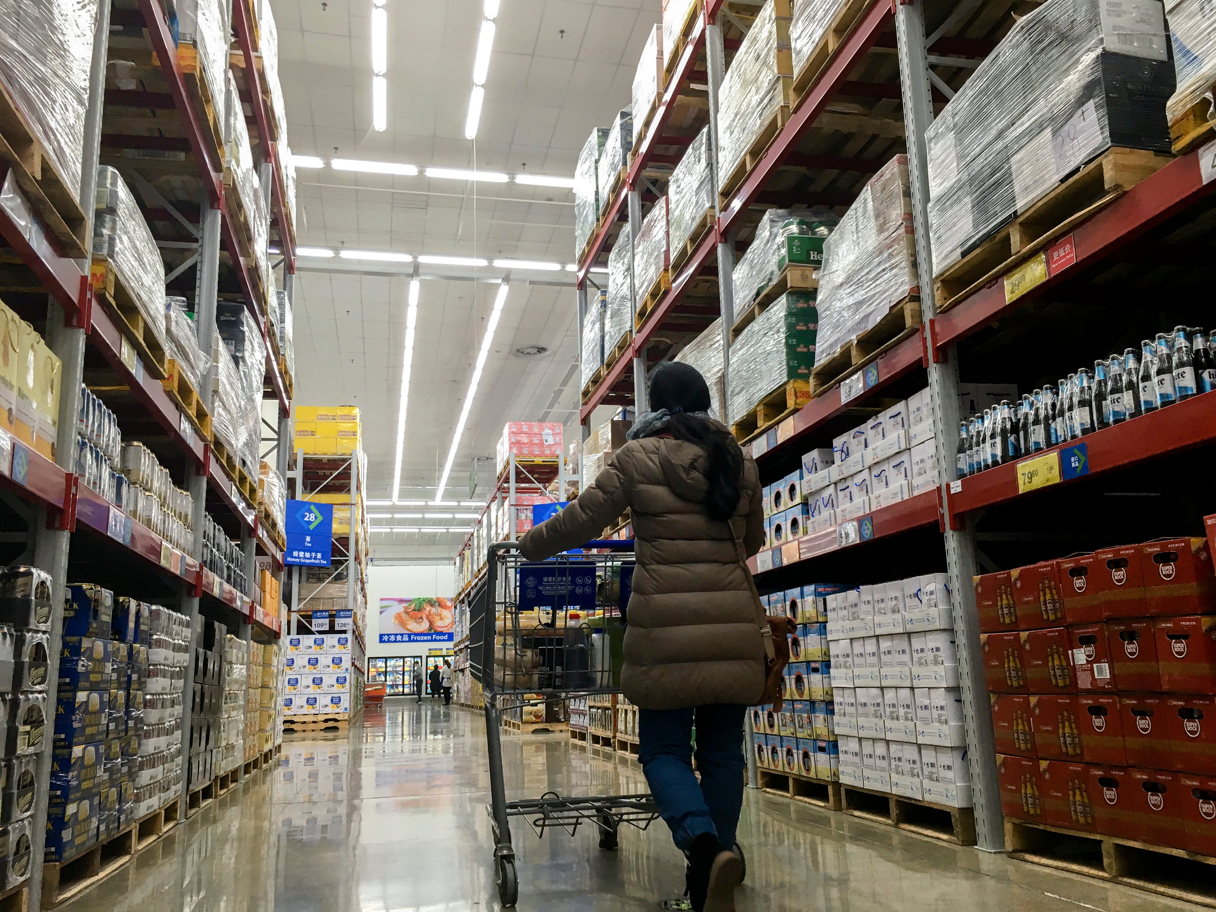 a woman walking down the aisles at a Sam's Club