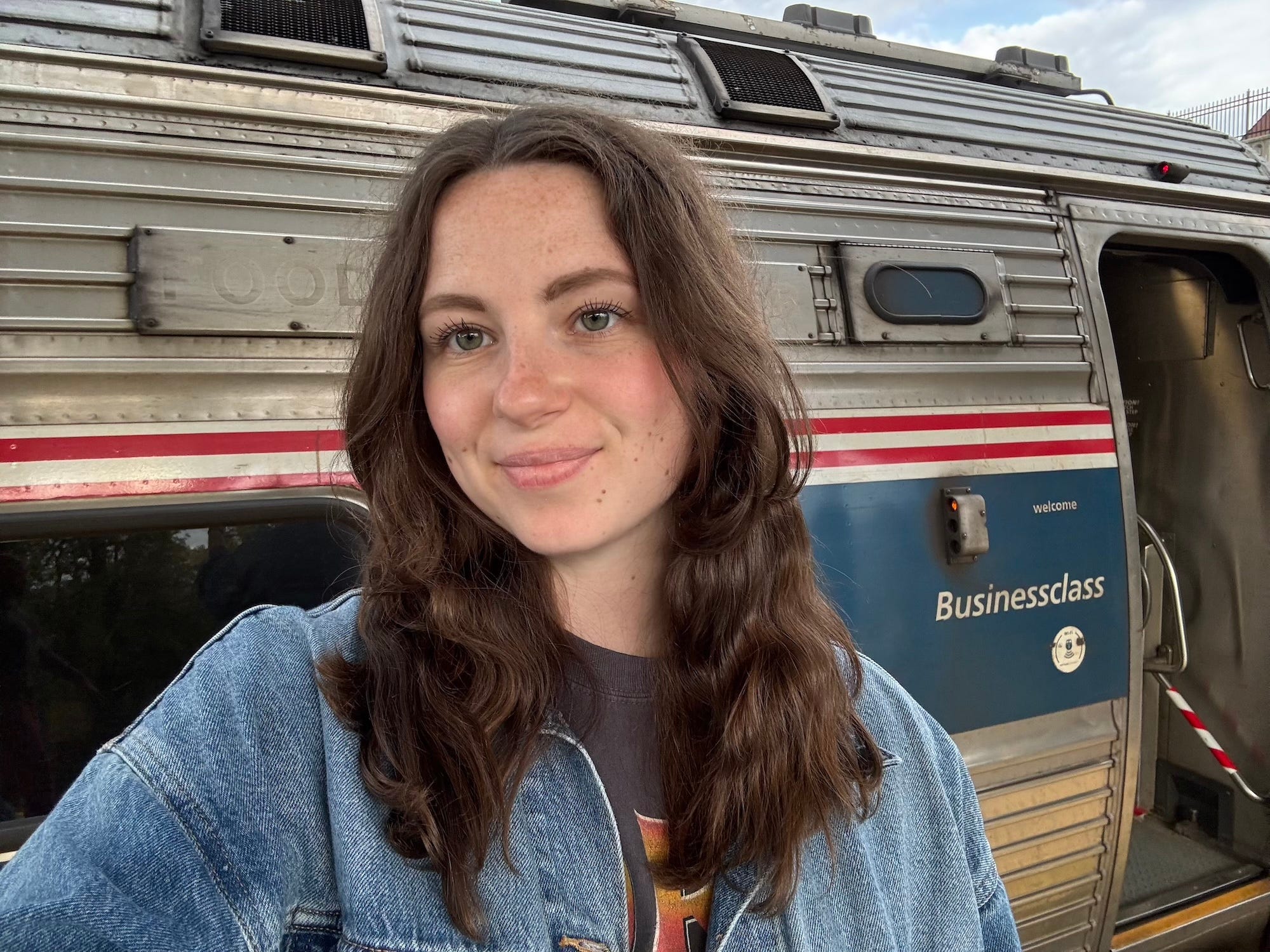 A selfie of a woman in front of a Business Class car on an Amtrak train.