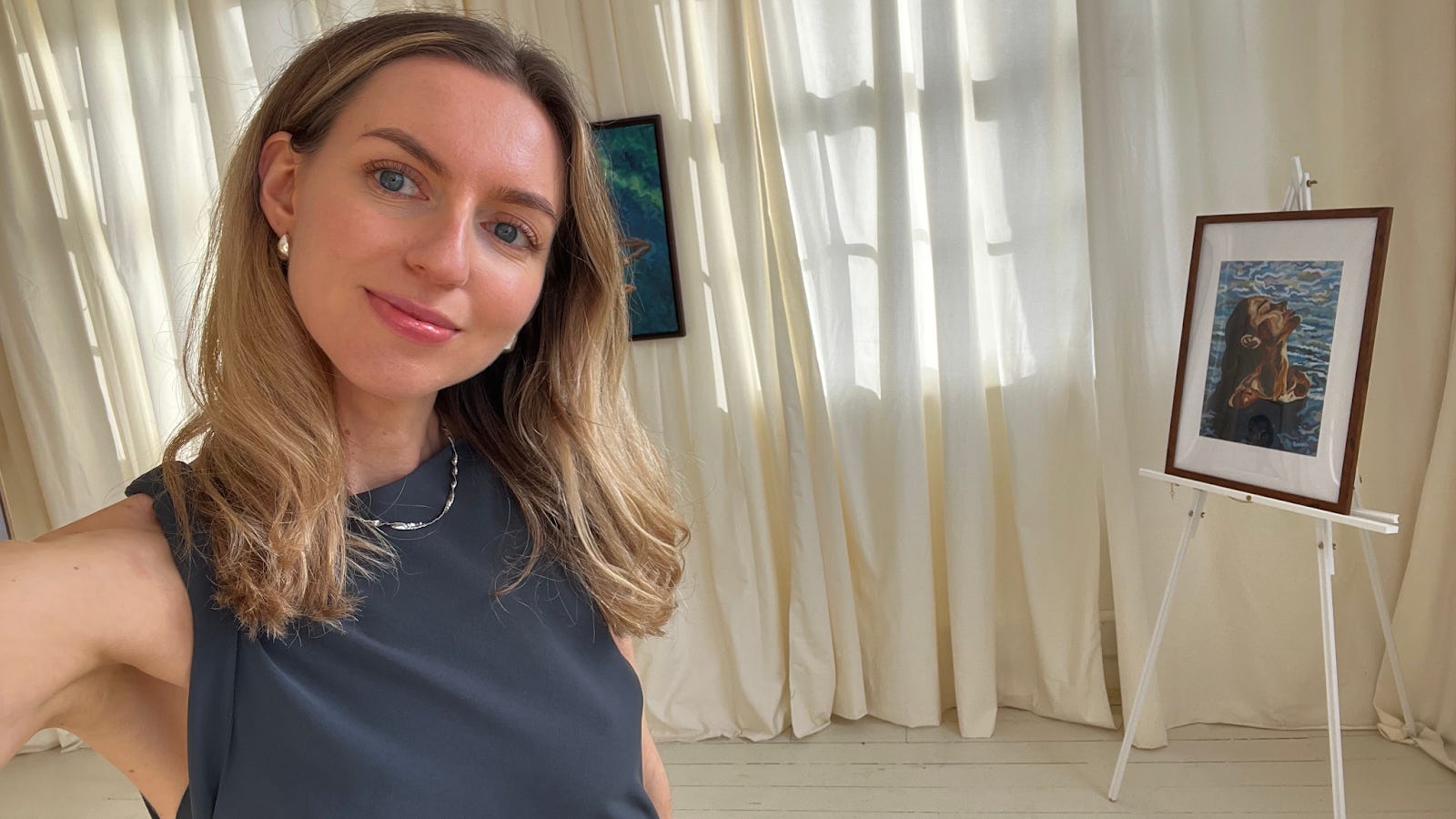 a woman takes a selfie with one of her paintings