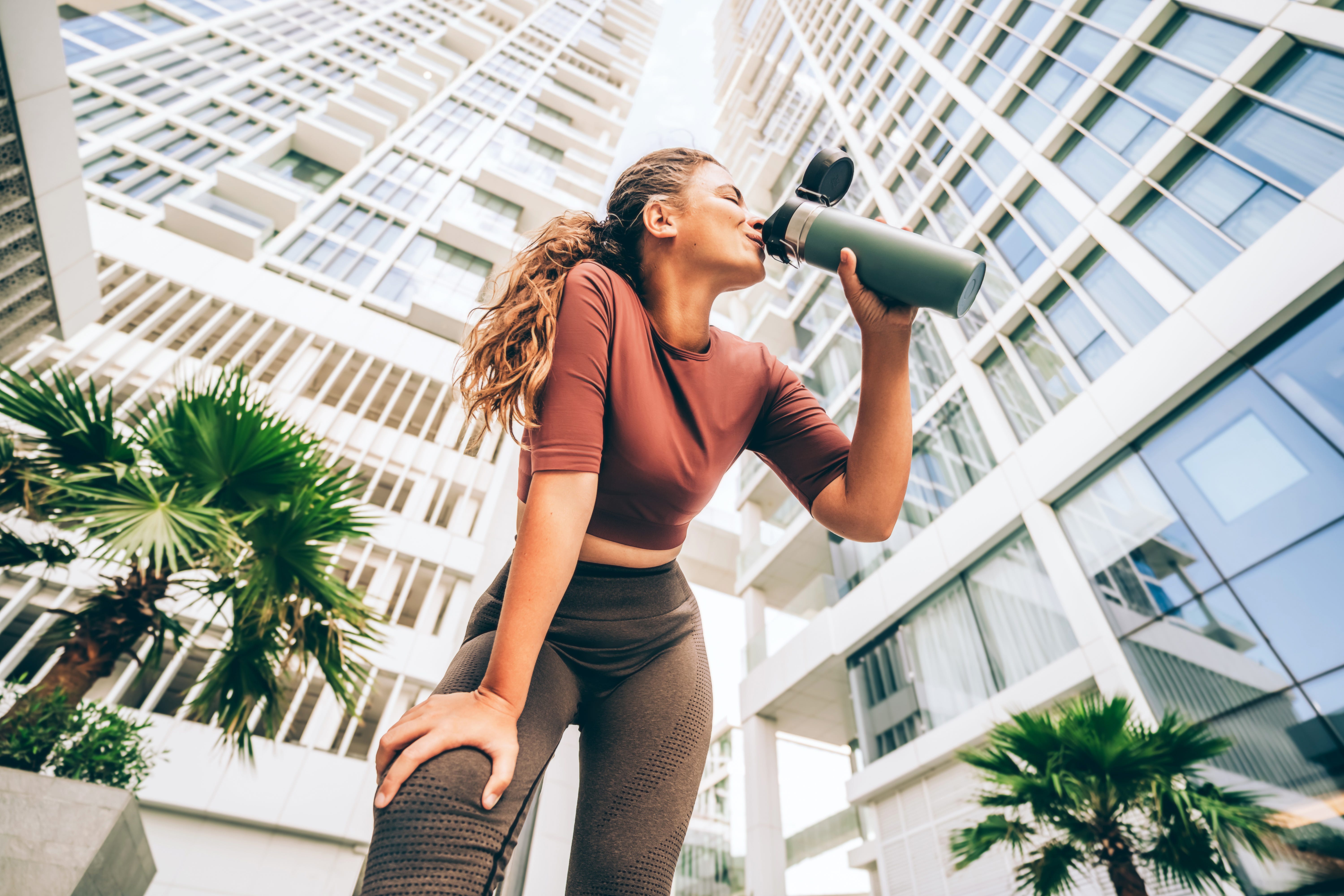 woman in fitness attire drinking from water bottle