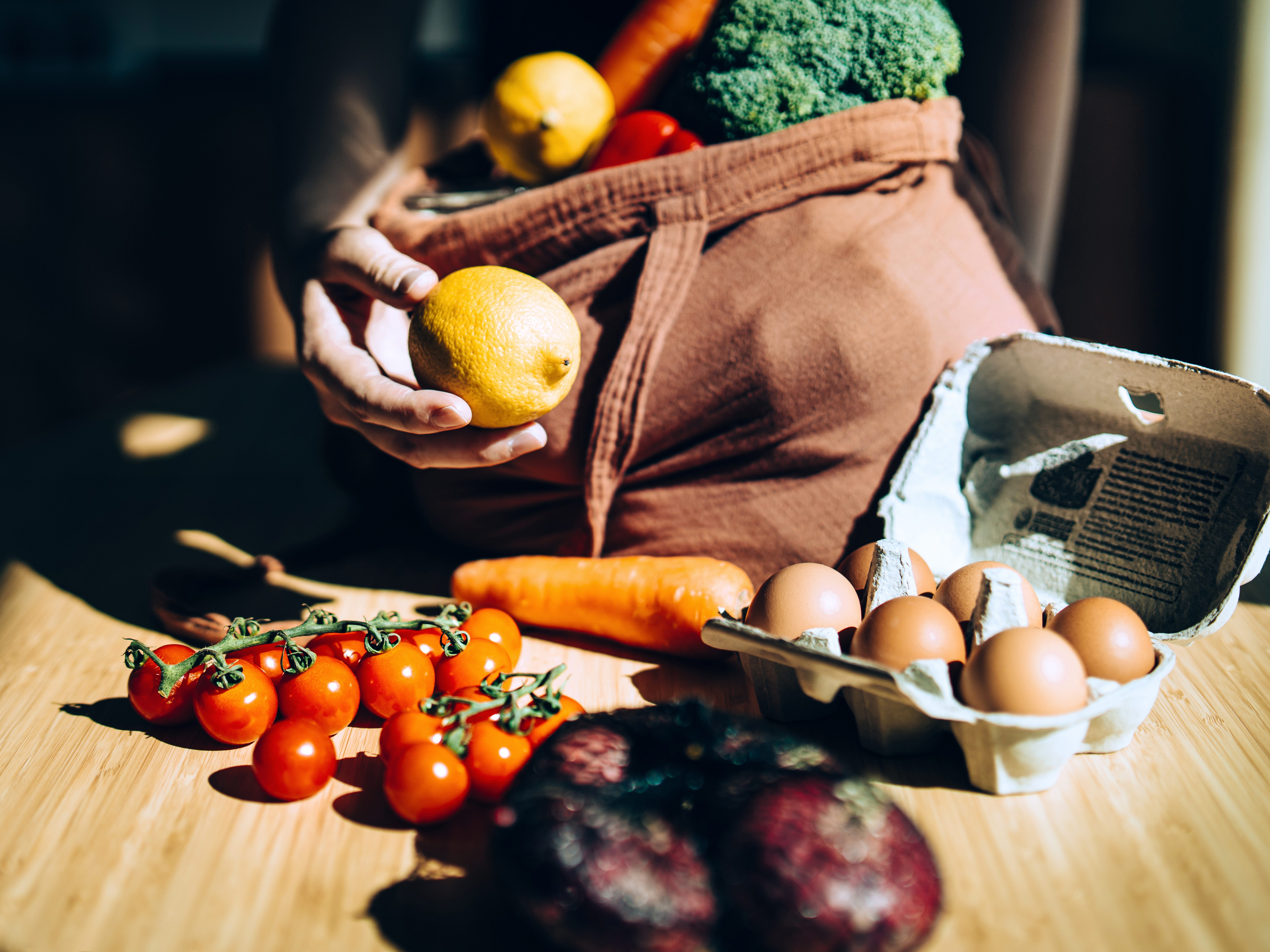 Woman removing groceries from tote bag.