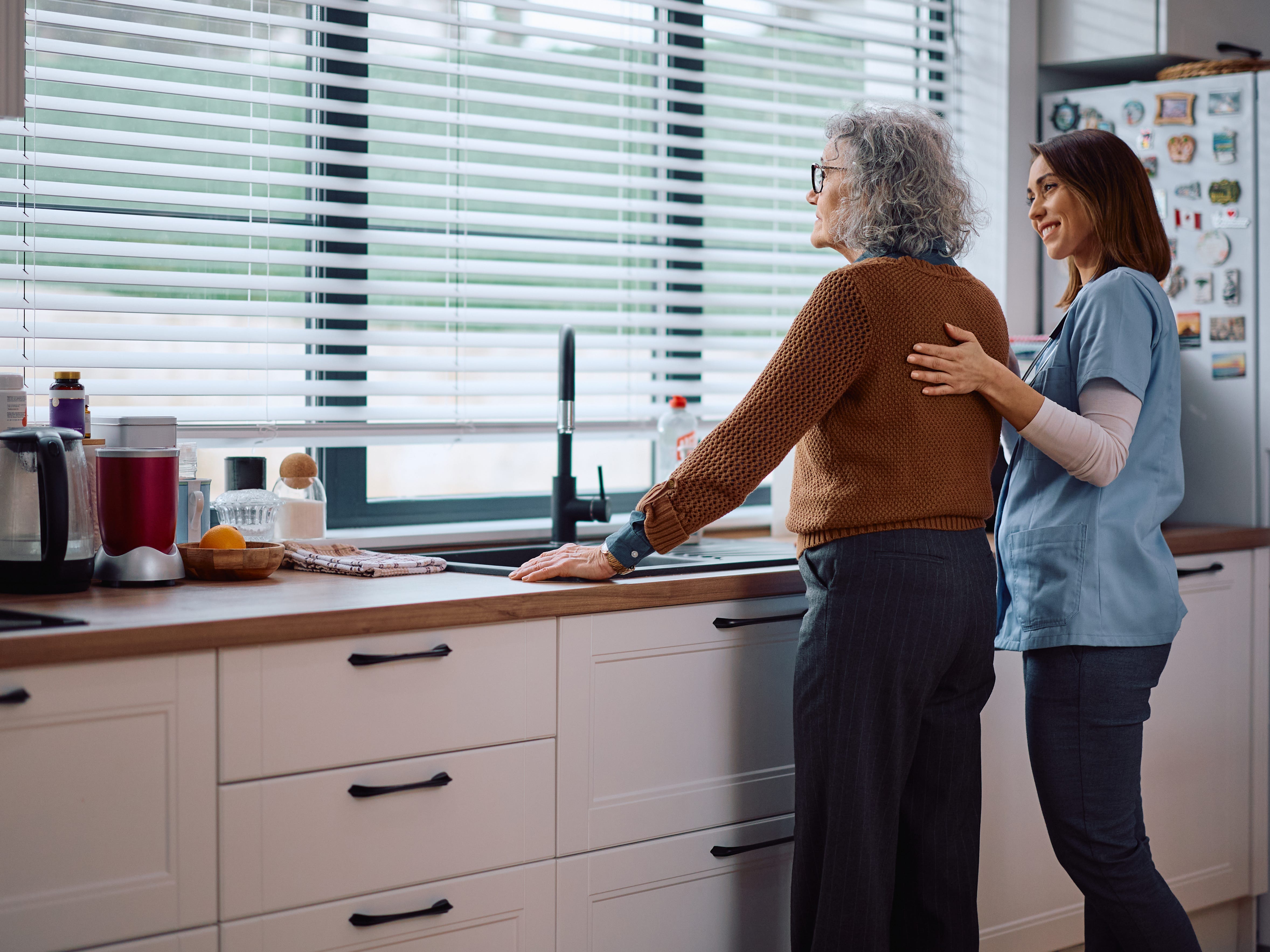 a nurse caregiver helping an elderly woman in the kitchen