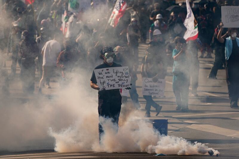 A demonstrator holds a sign amid tear gas as people protest against U.S. President Donald Trump's policies and federal immigration sweeps during a No Kings Day demonstration in Los Angeles.
