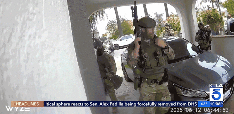 A masked U.S. Immigration and Customs Enforcement agent turns an outdoor camera away during a raid in Huntington Park, California.