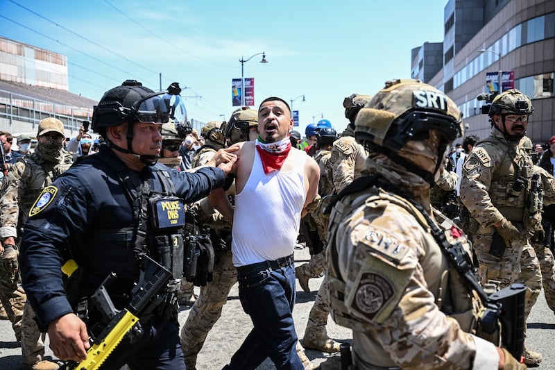 Law enforcement officers, including members of the Immigration and Customs Enforcement (ICE) Special Response Team and Homeland Security agents, arrest a demonstrator outside the Federal Building in Los Angeles.