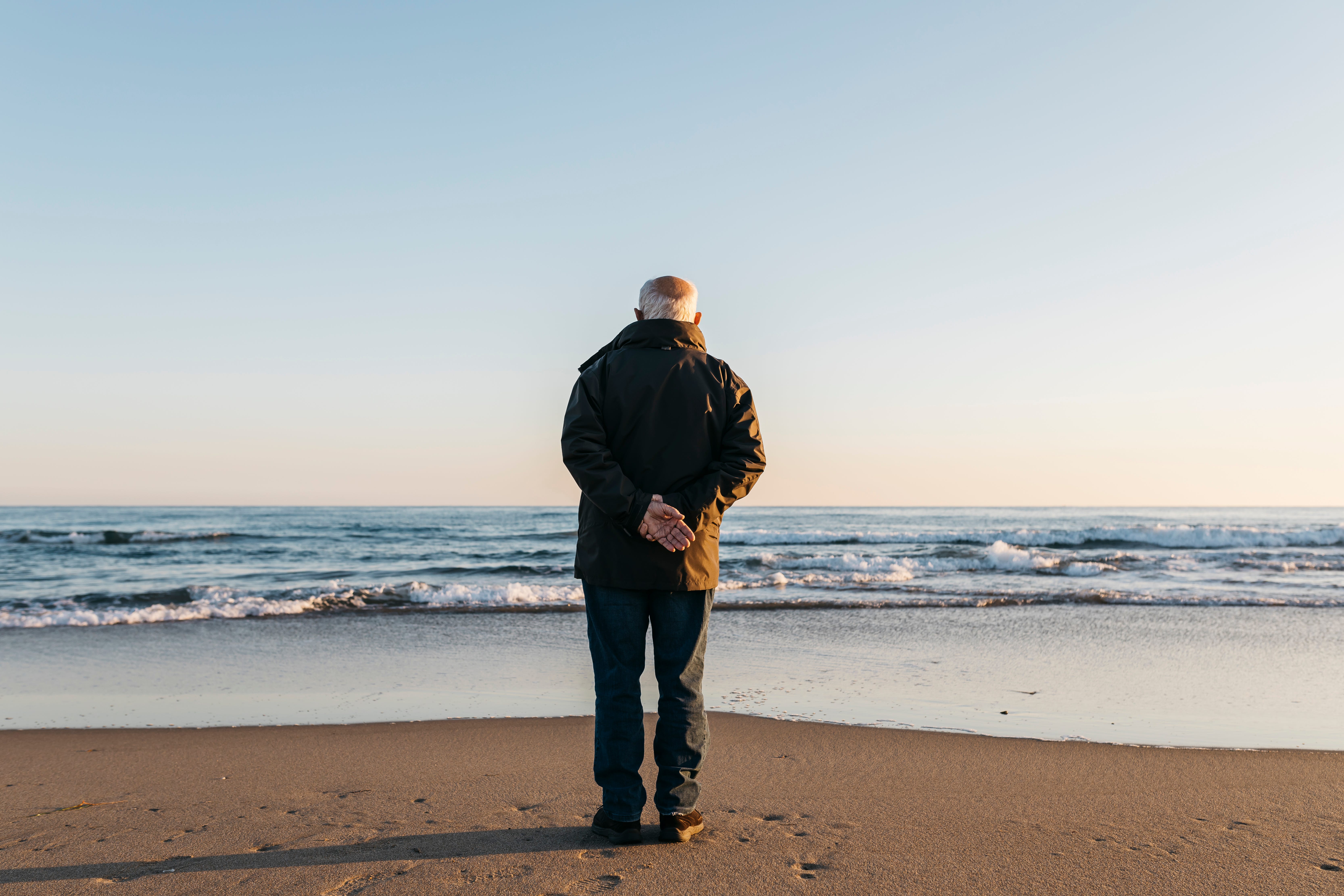 Old man standing staring at the ocean