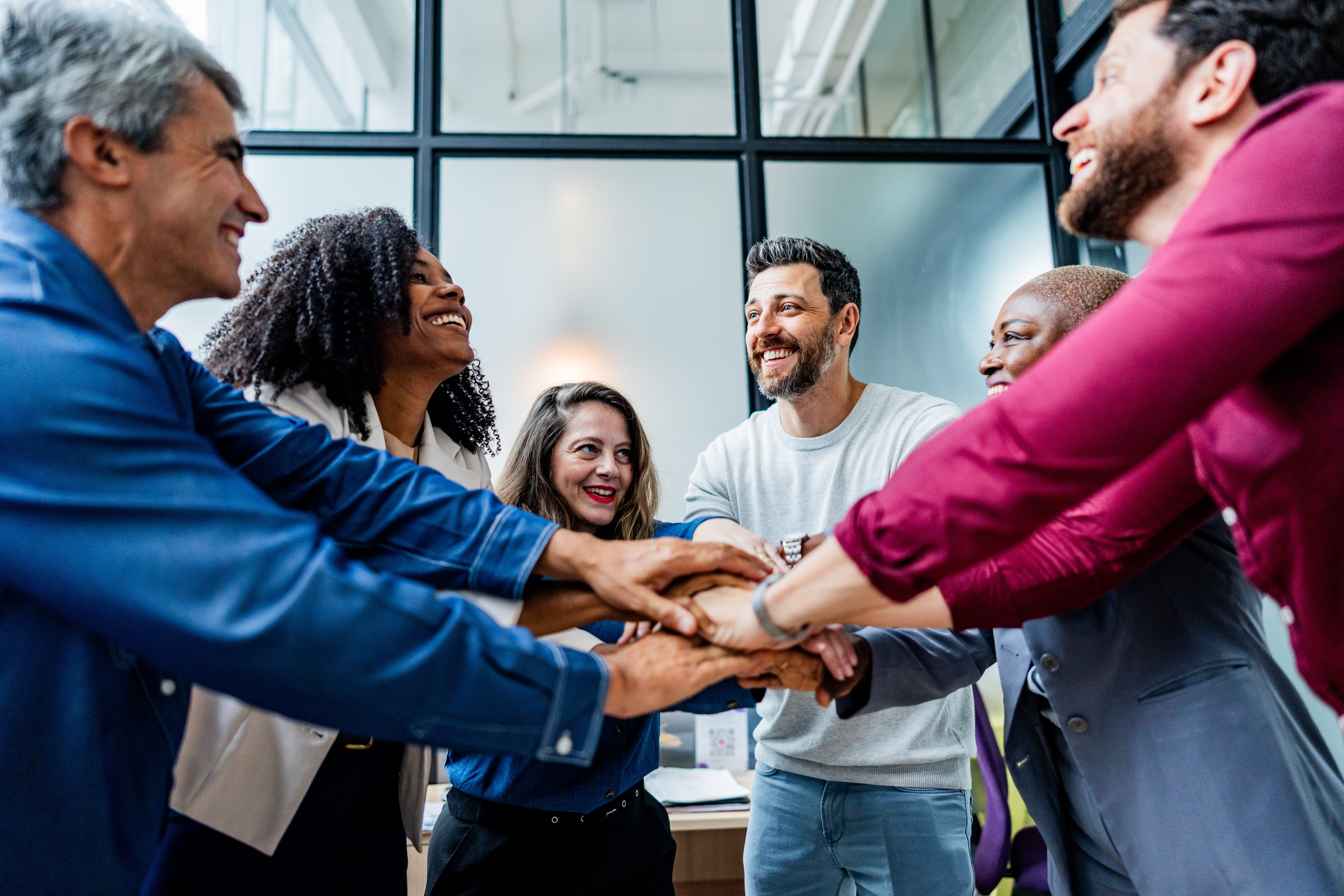 A group of professionals gathered around with their hands in an inner circle to show team spirit.
