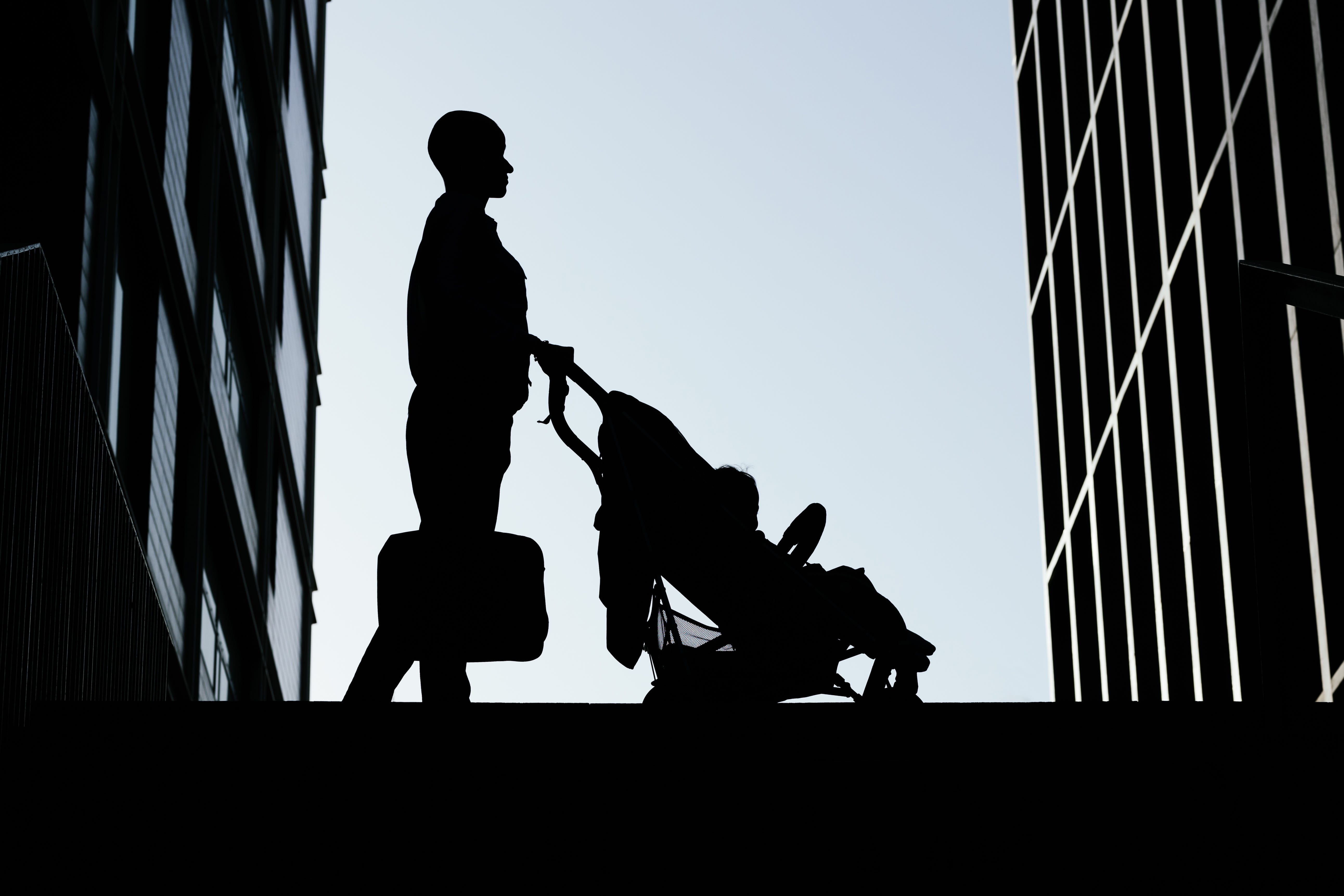 Silhouette of modern woman on her way home with her baby in a stroller
