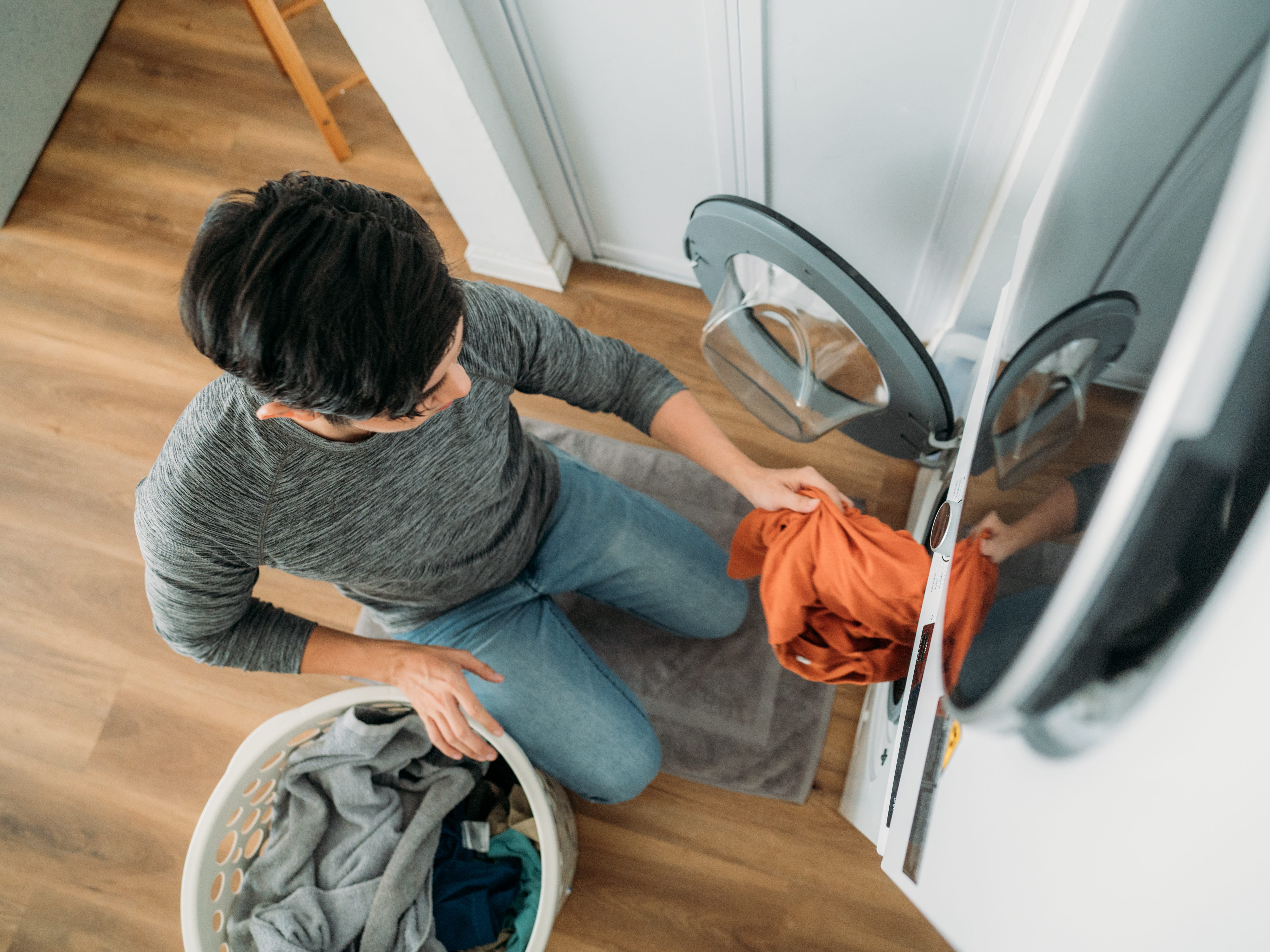 overhead view of a man putting laundry into a washing machine