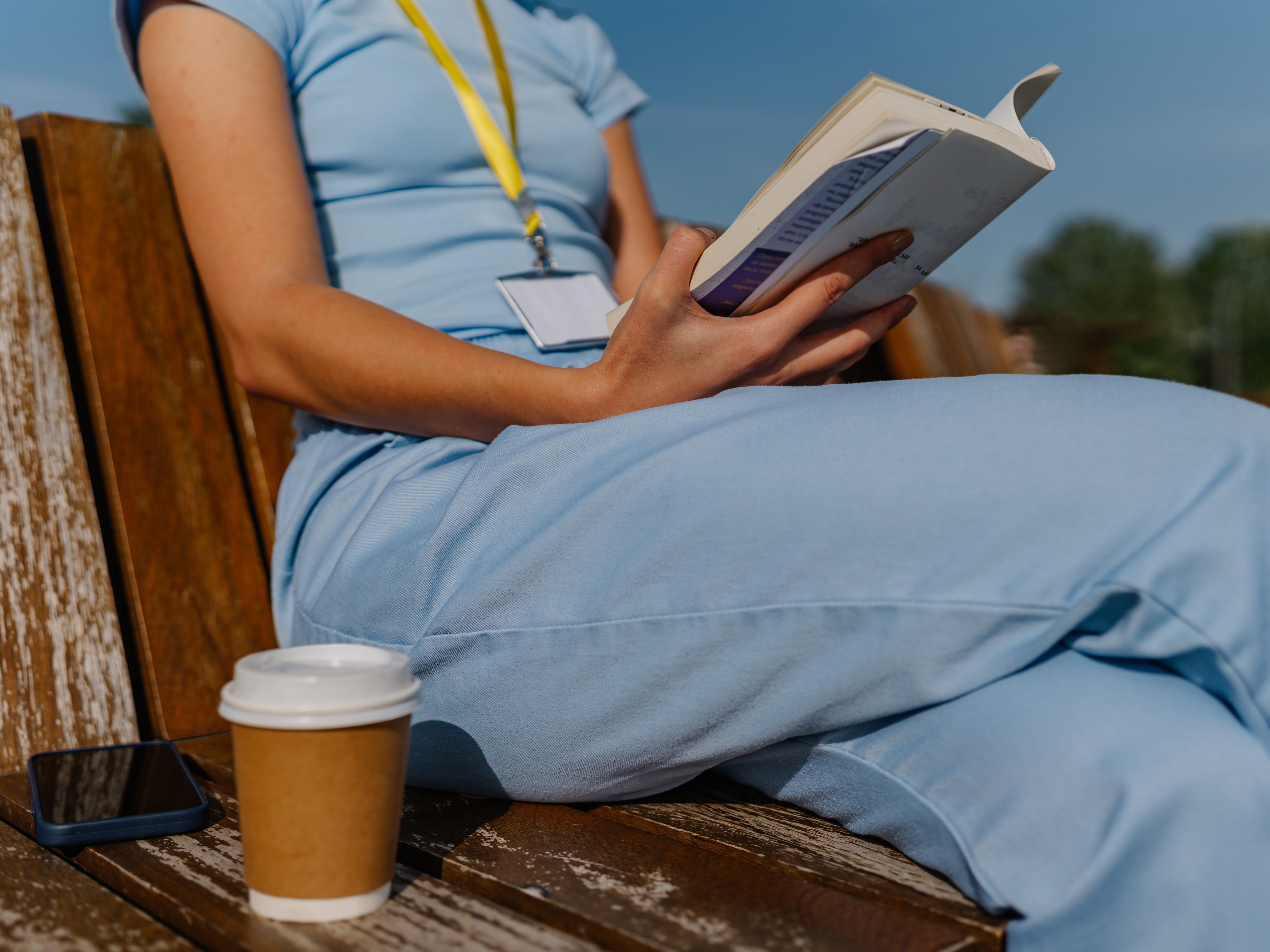 a woman in scrubs sitting on a bench and reading abook