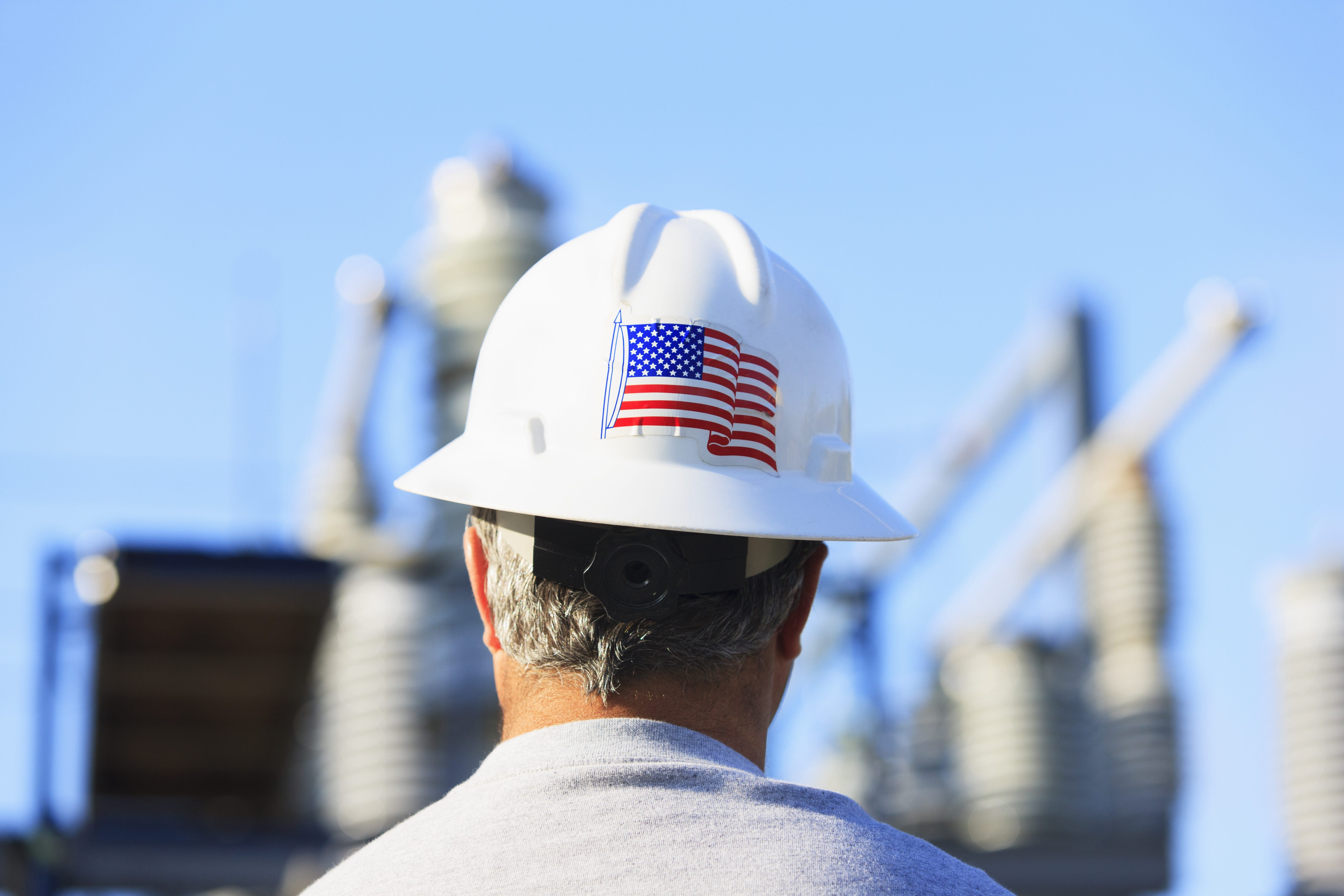 A construction worker's hat has a United States flag stocker on it.