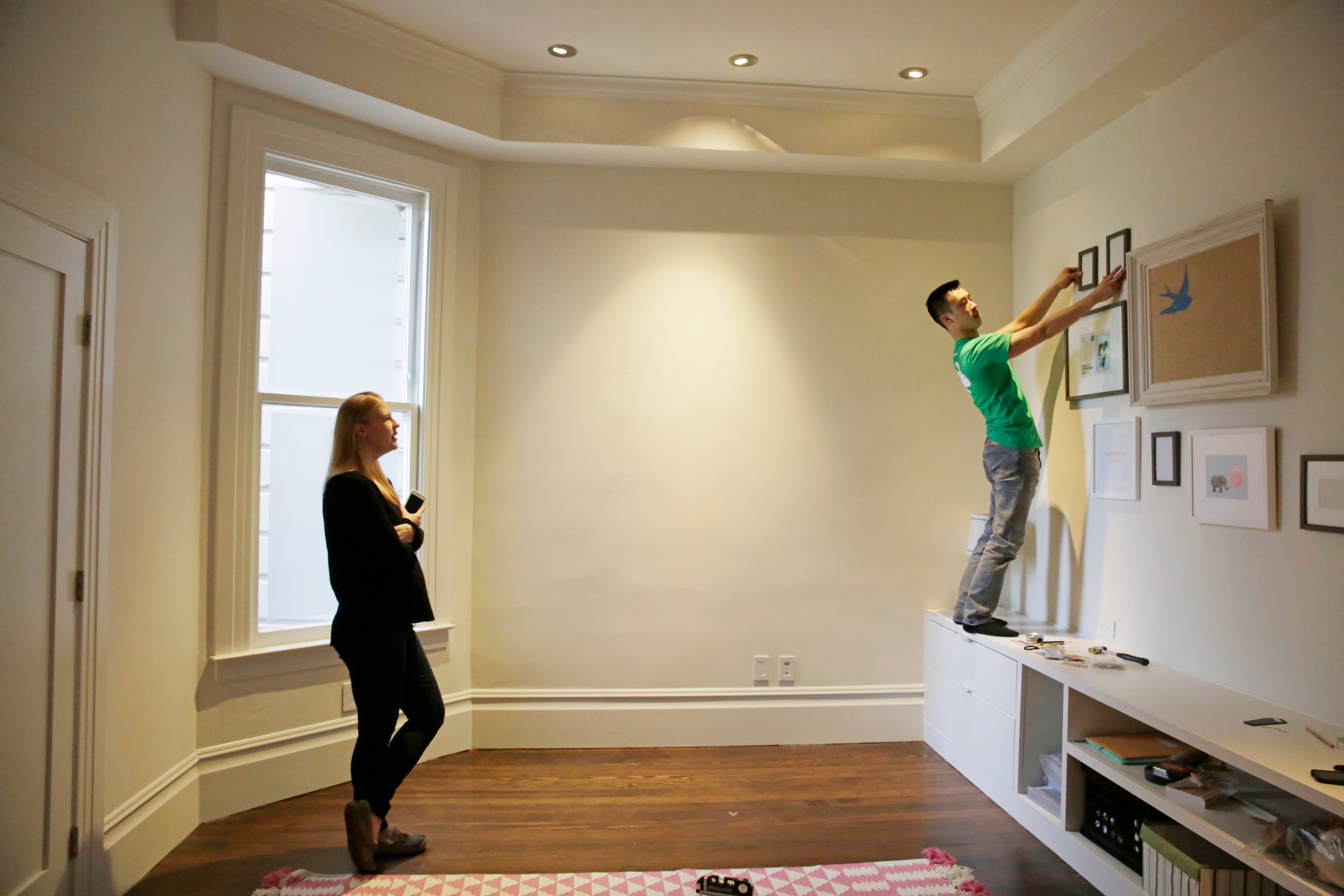 A TaskRabbit "Tasker" helps a client with frames on a wall.