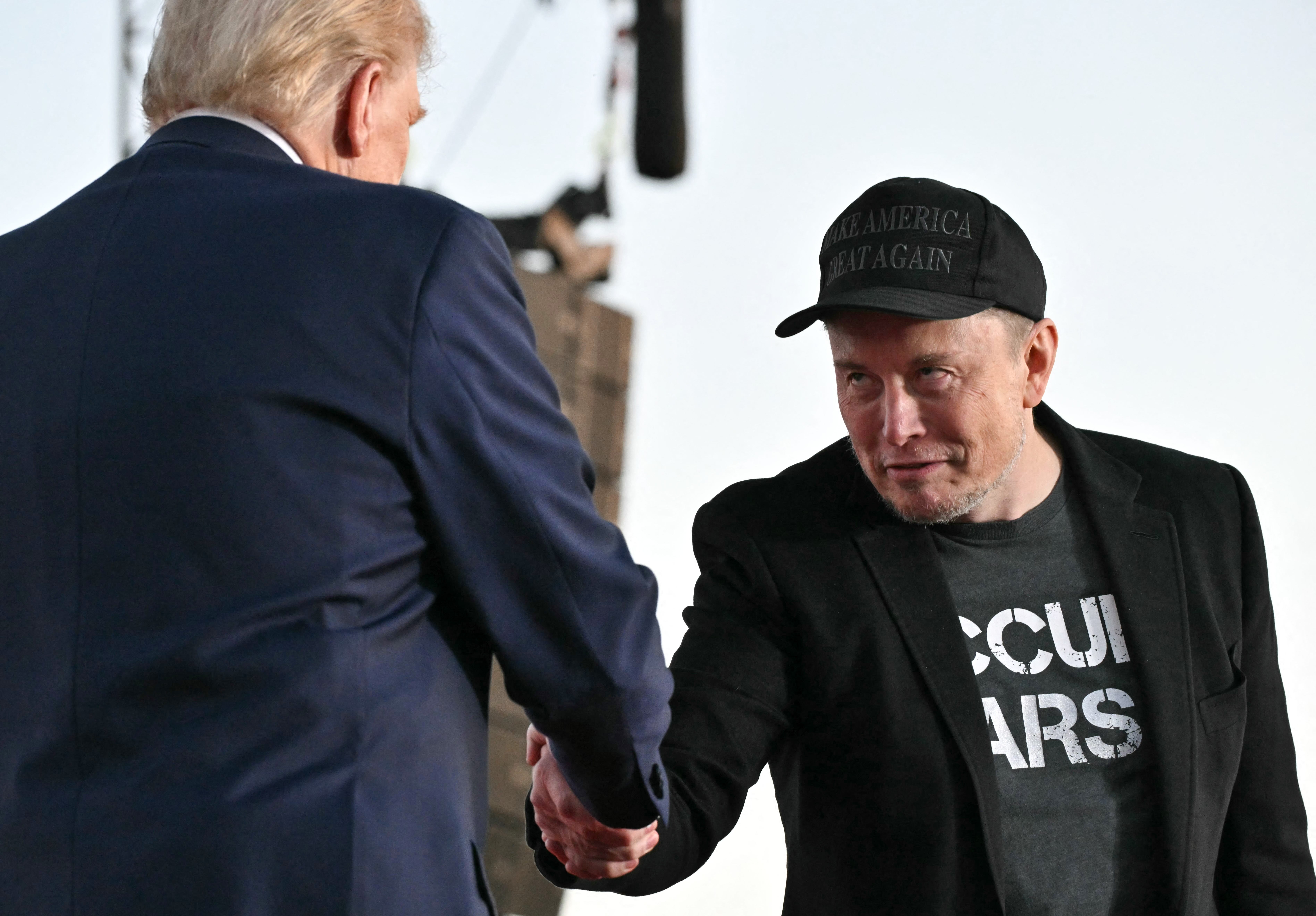 Elon Musk shakes Donald Trump's hand.