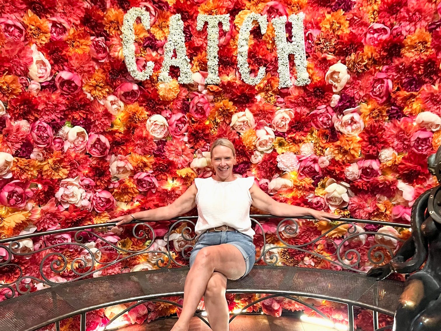Author Wendy Lee posing at Catch in front of wall of roses