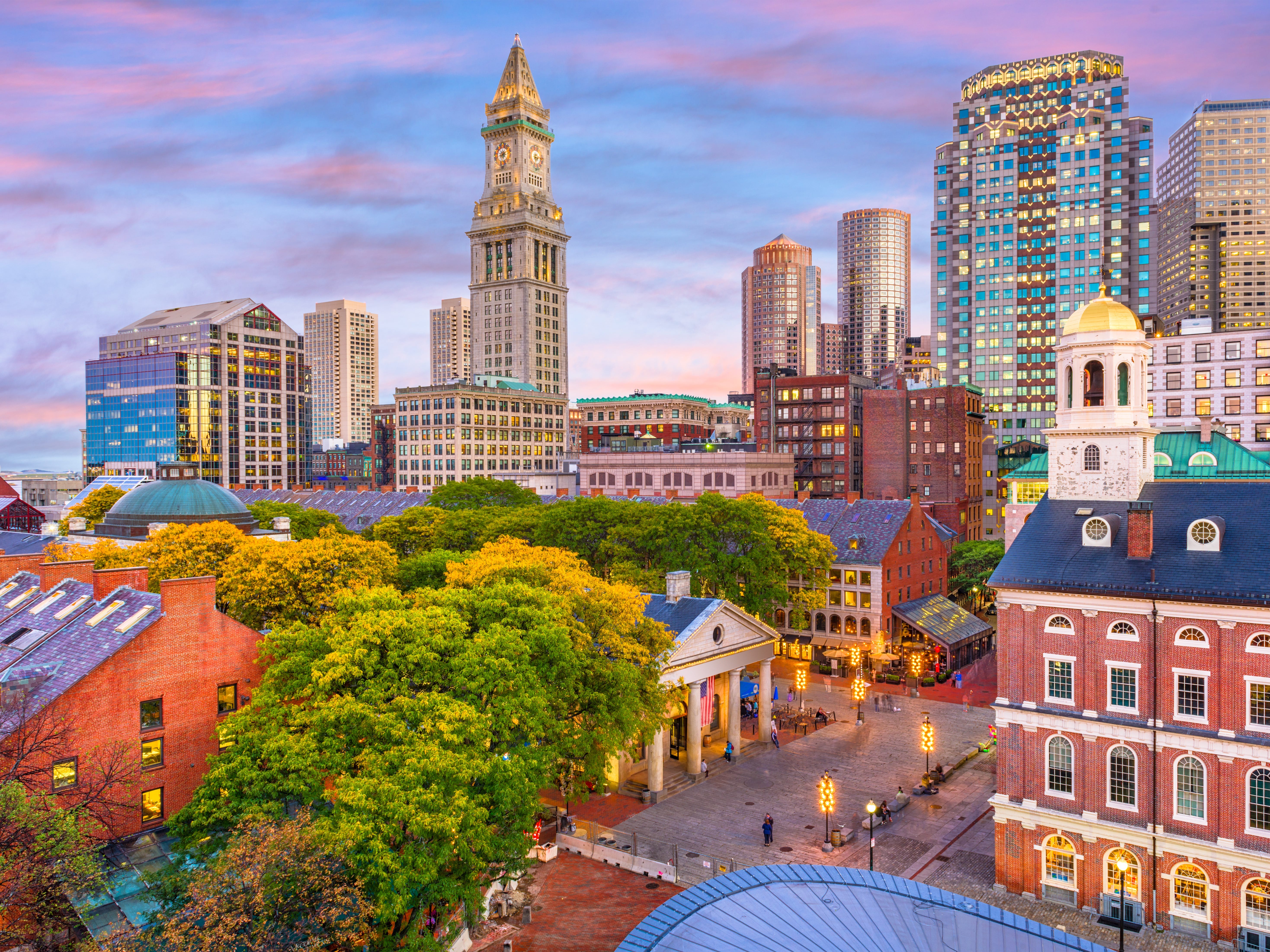 An aerial view of historic buildings and skyscrapers in Boston at sunset.