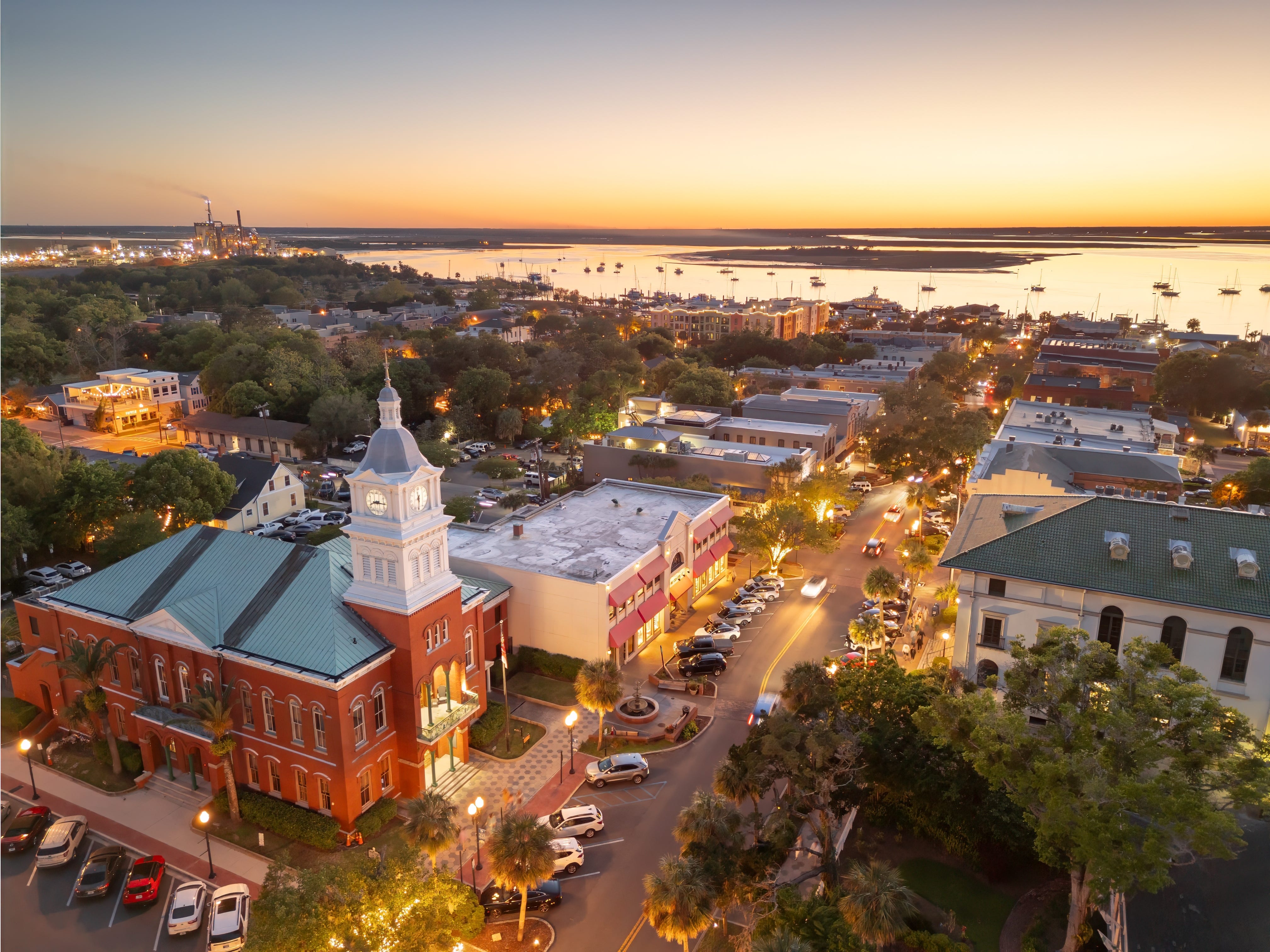 An aerial view of a beach town with a church and shops at sunset.