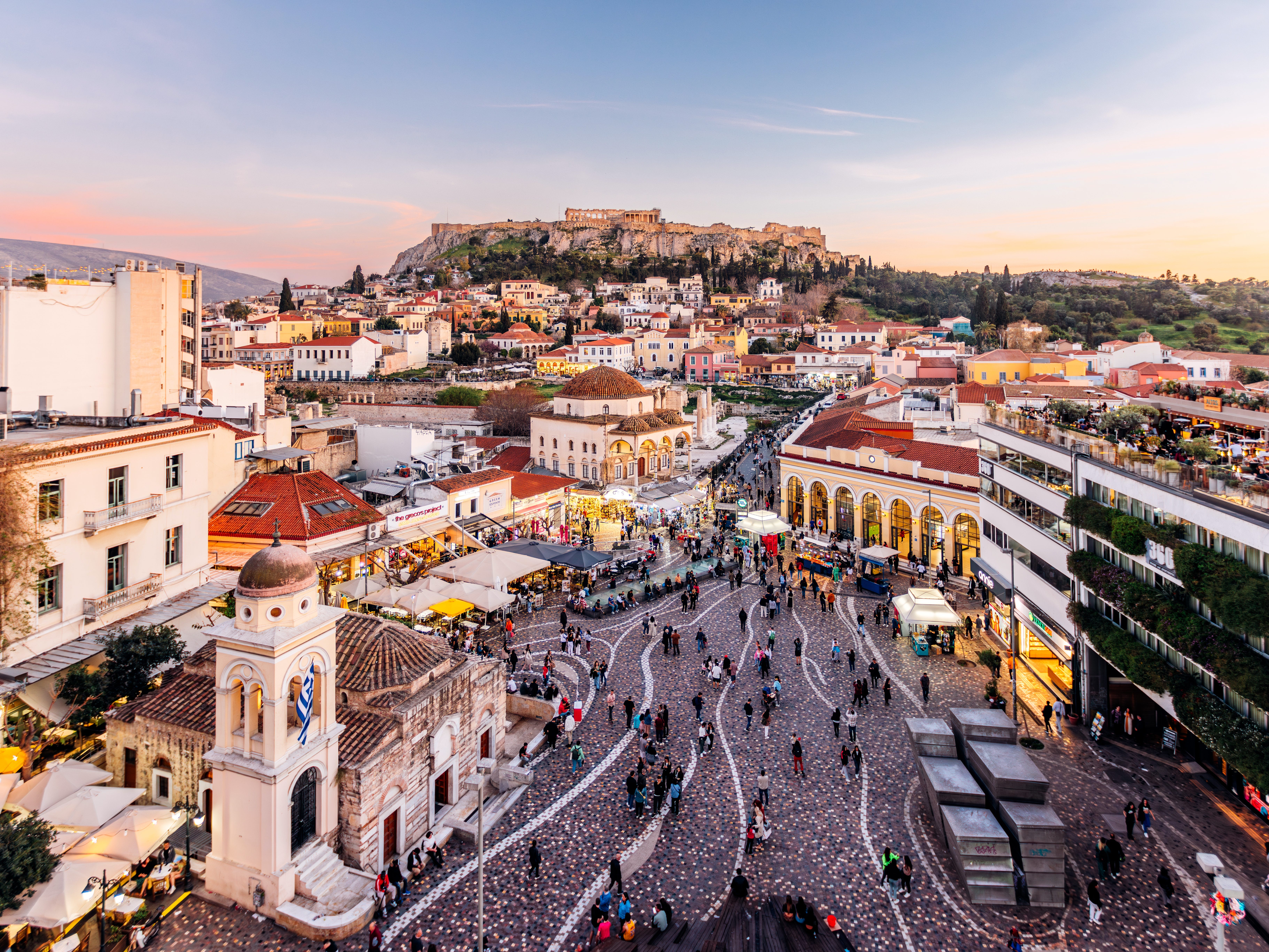 An aerial view of Athens at dusk, with the Acropolis in the distance.