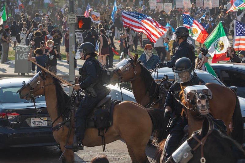 Mounted police officers charge their horses into a crowd on the street to clear an area near City Hall's Los Angeles.