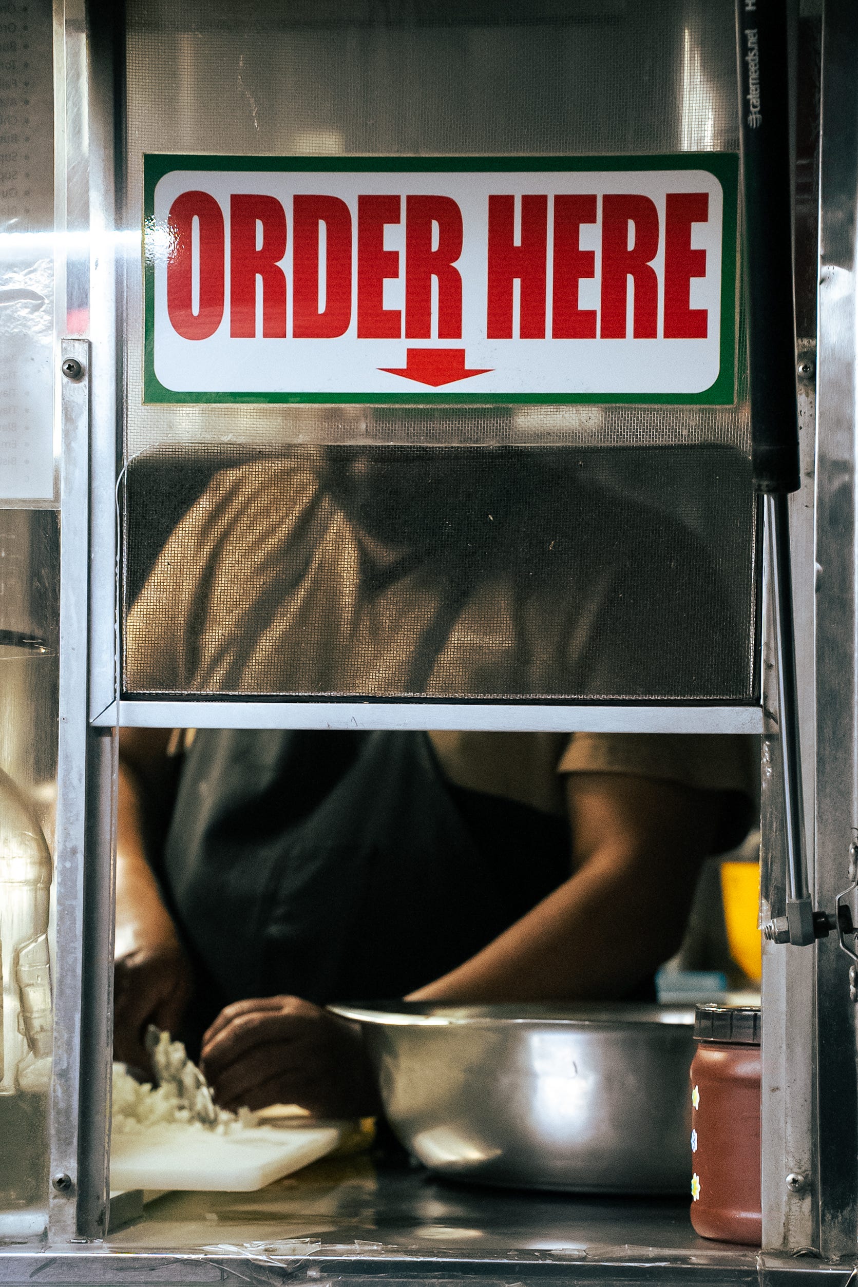 A person in a taco truck chops onions.