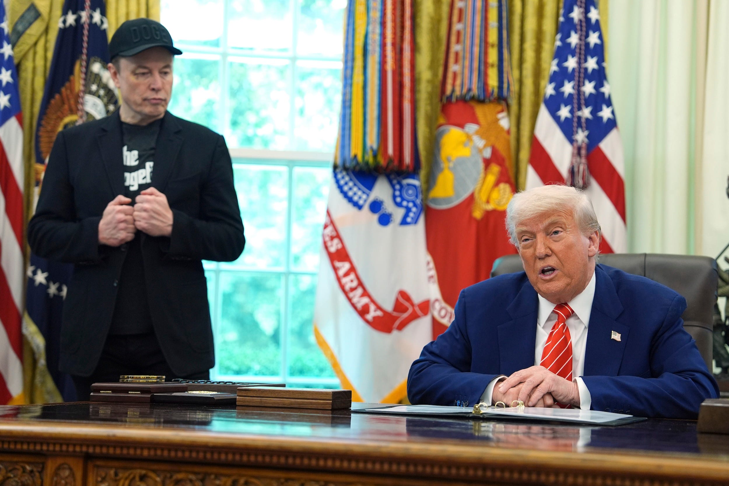 Elon Musk looks over at Donald Trump during his final appearance in the Oval Office