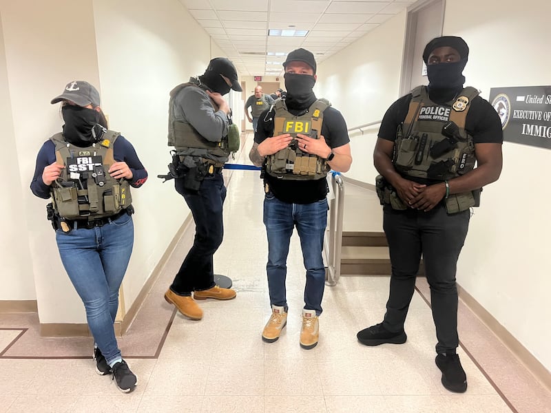 Four law enforcement officers in vests marked Police and FBI, all wearing masks