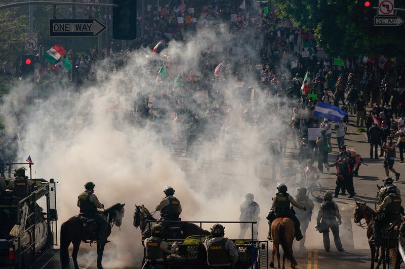 Mounted police operate amid tear gas as people protest during a No Kings Day demonstration in Los Angeles, California.
