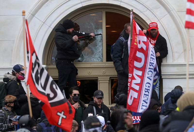 A man breaks a window as a mob of supporters of U.S. President Donald Trump storm the U.S. Capitol Building in Washington, U.S., January 6, 2021